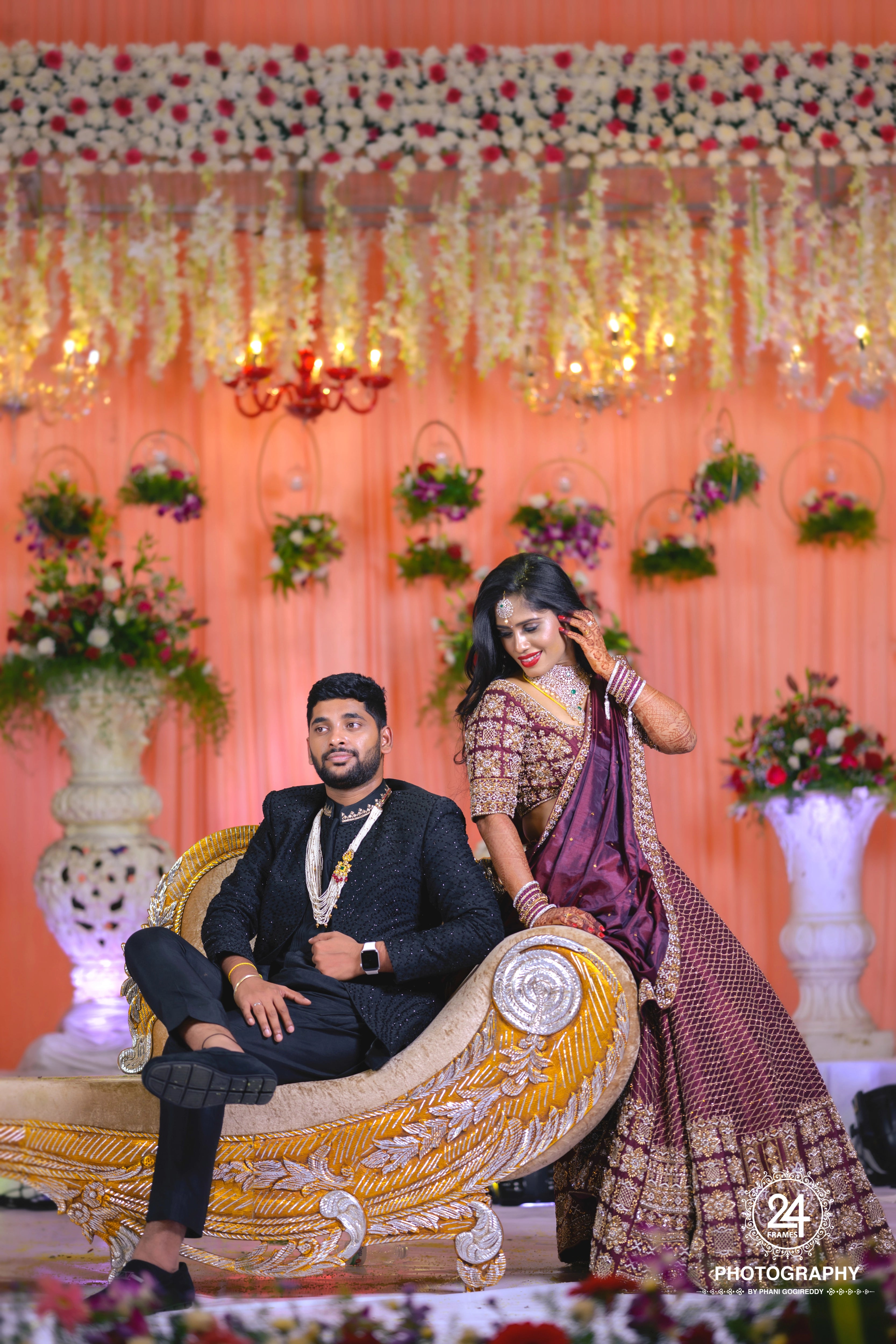 Bride Chaitanya Reddy posing with groom in a maroon raw silk reception lehenga, handcrafted by team Archana Karthick.