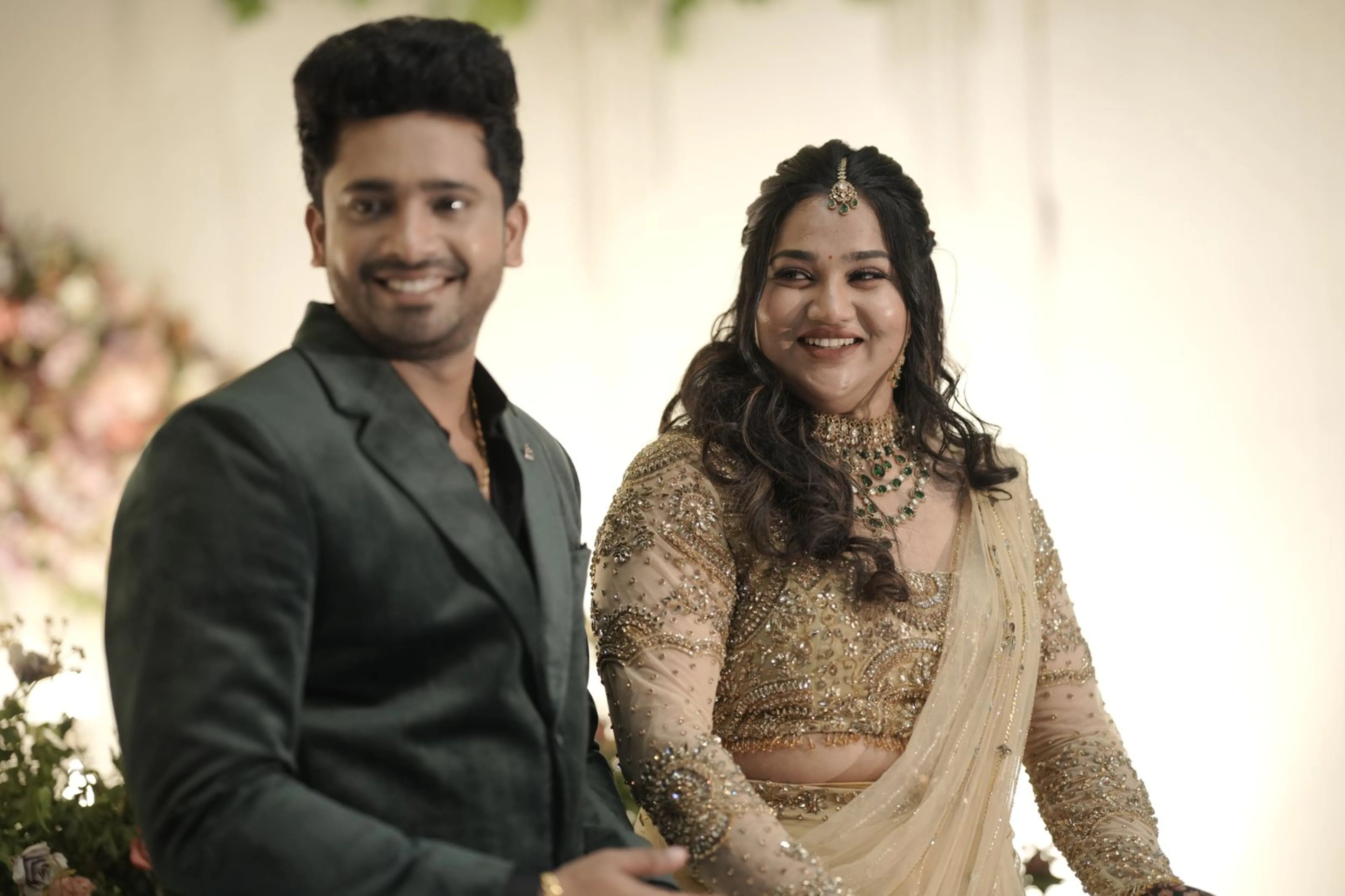 Bride Chithira from Australia, smiling with groom in a golden tulle saree by team Archana Karthick.