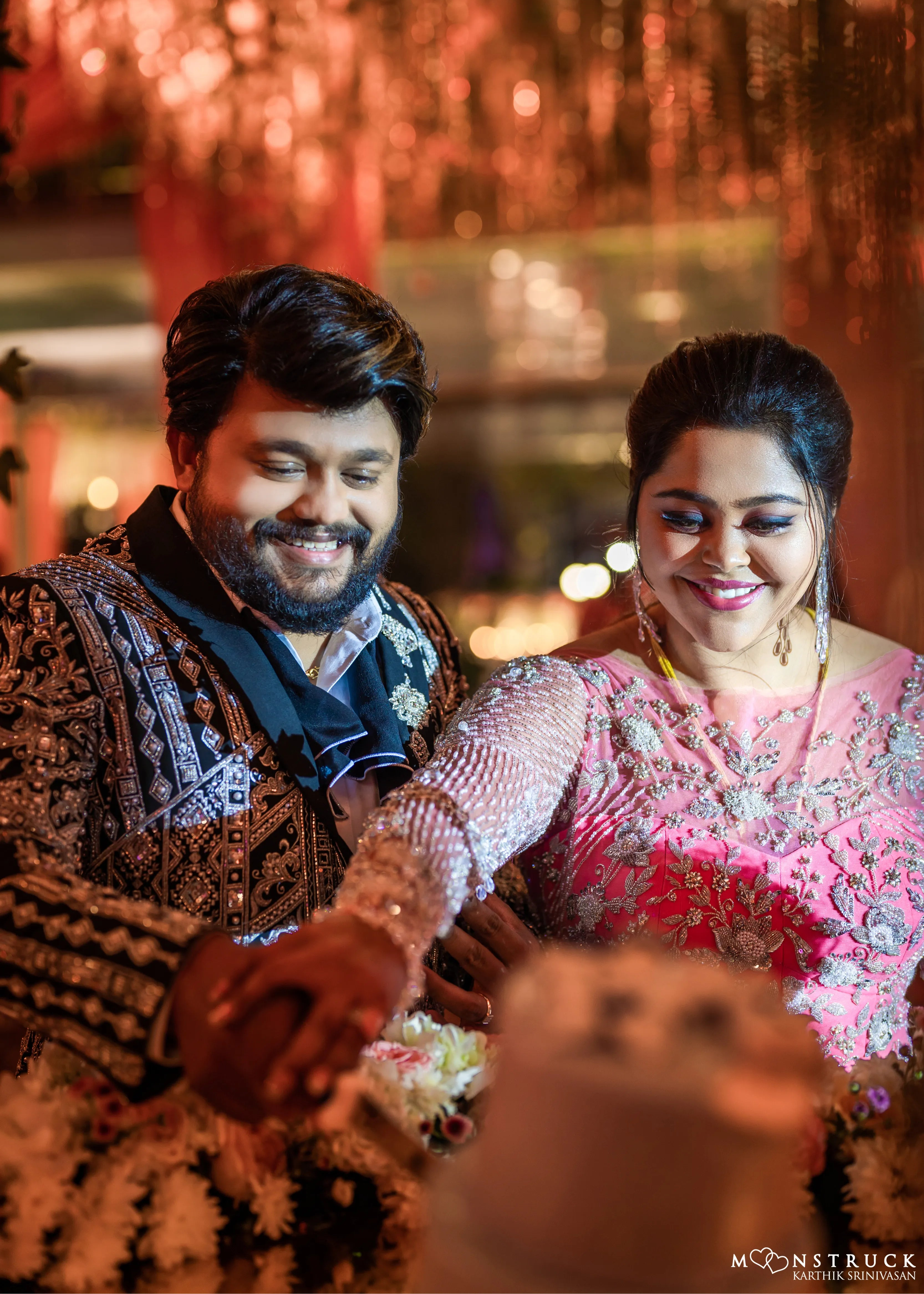 Bride (Coimbatore) in handcrafted pink tulle gown and and Groom (Chennai) in embeliished jacket for their reception cutting the cake.