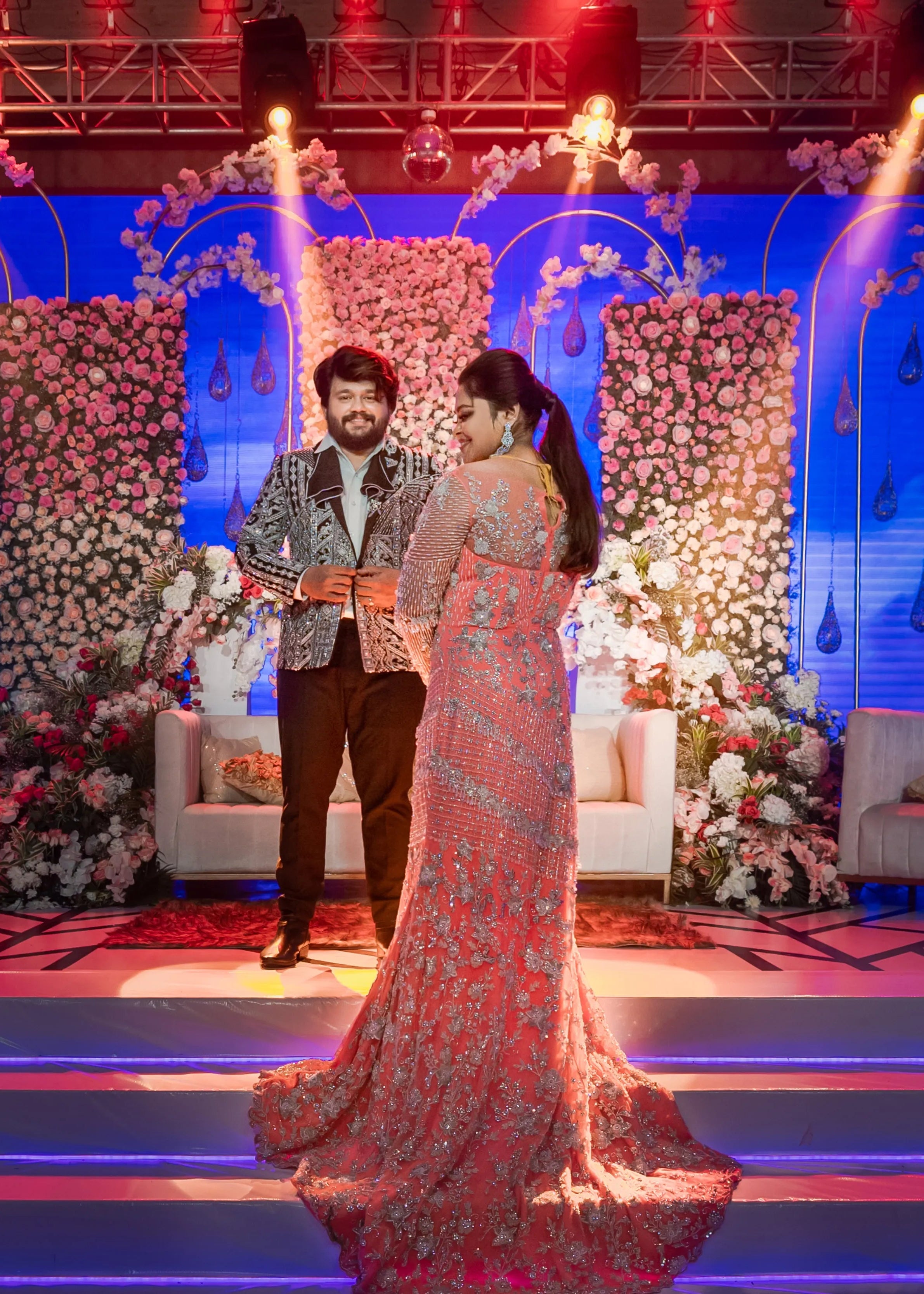 Bride (Coimbatore) in handcrafted pink tulle gown and and Groom (Chennai) in embeliished jacket for their reception photoshoot on stage.