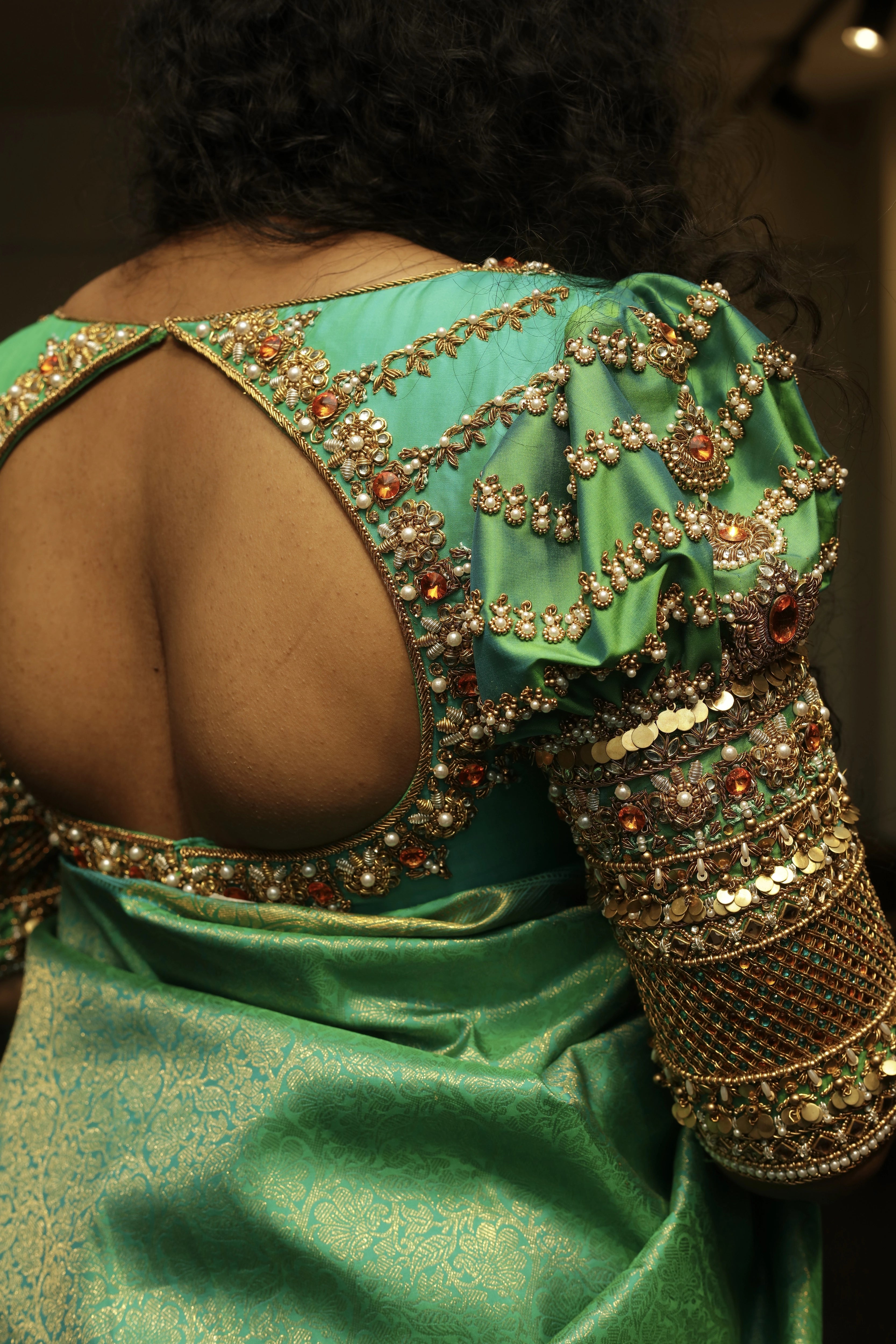 Bride Cris showcasing back blouse design in a sea green puff sleeved silk blouse & belt, tulle veil, handcrafted with appliques, beads, kundan, stones, crystals, etc by team Archana Karthick
