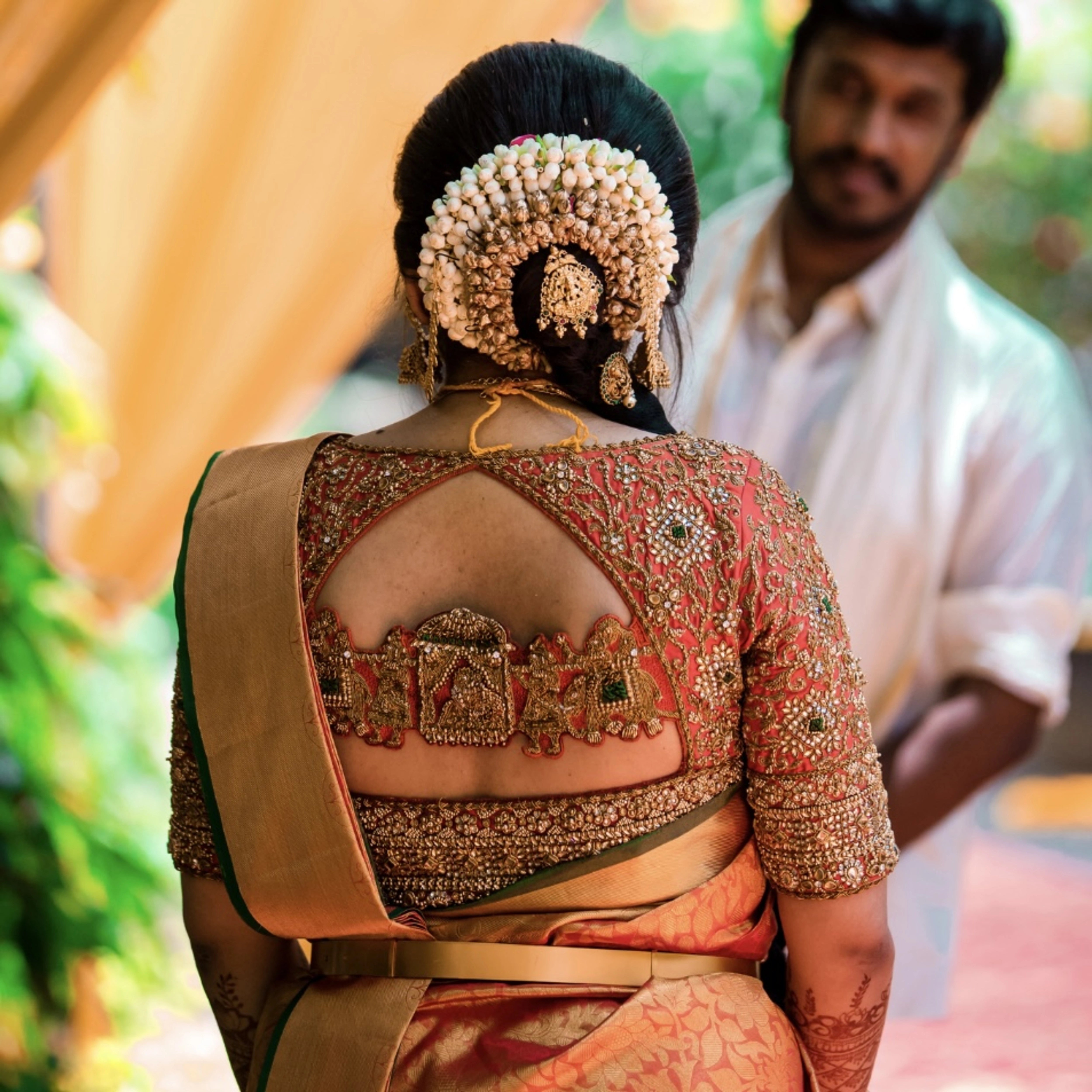 Bride Deepachitra posing in a vermilion silk blouse with the palanquin concept. Intricately handcrafted with stones, resham, zardozi, beads and cutdana by team Archana Karthick.