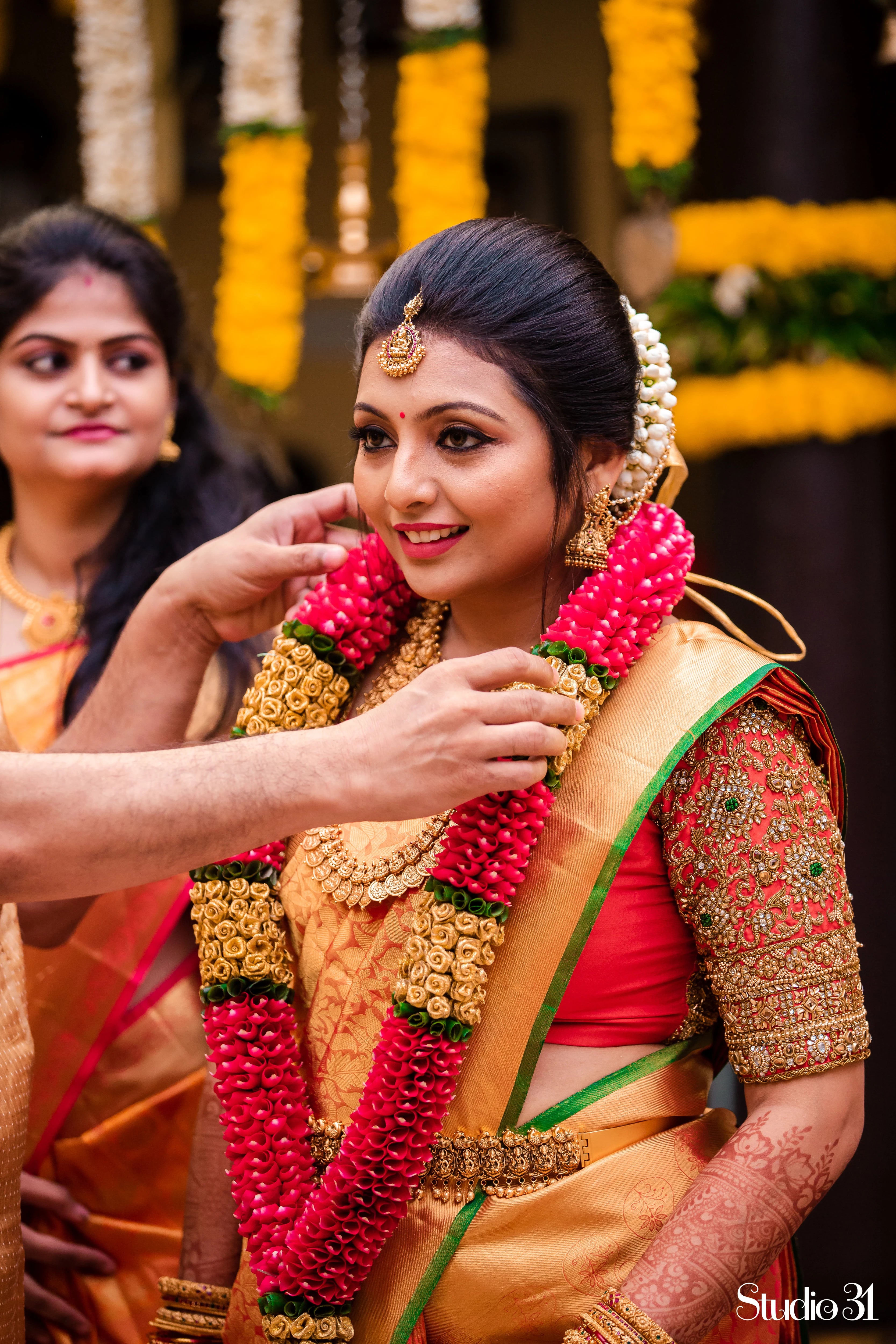 Bride Deepachitra smiling in a vermilion silk blouse with the palanquin concept. Intricately handcrafted with stones, resham, zardozi, beads and cutdana by team Archana Karthick.