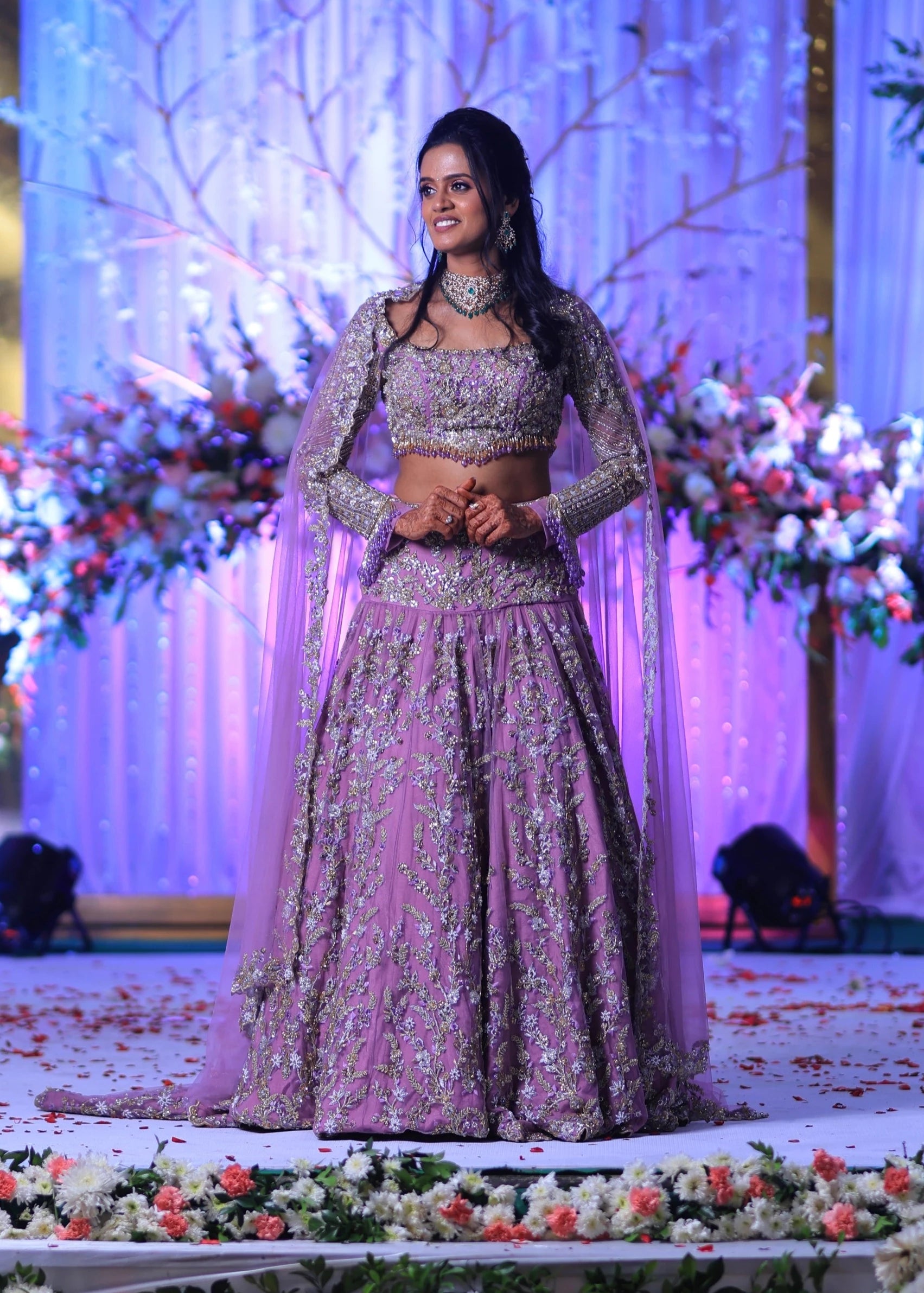 Bride Deepika on stage in lavender raw silk lehenga, intricately handcrafted with sequins, cutdana, beads, crystals, rhinestones and zardozi by team Archana Karthick.
