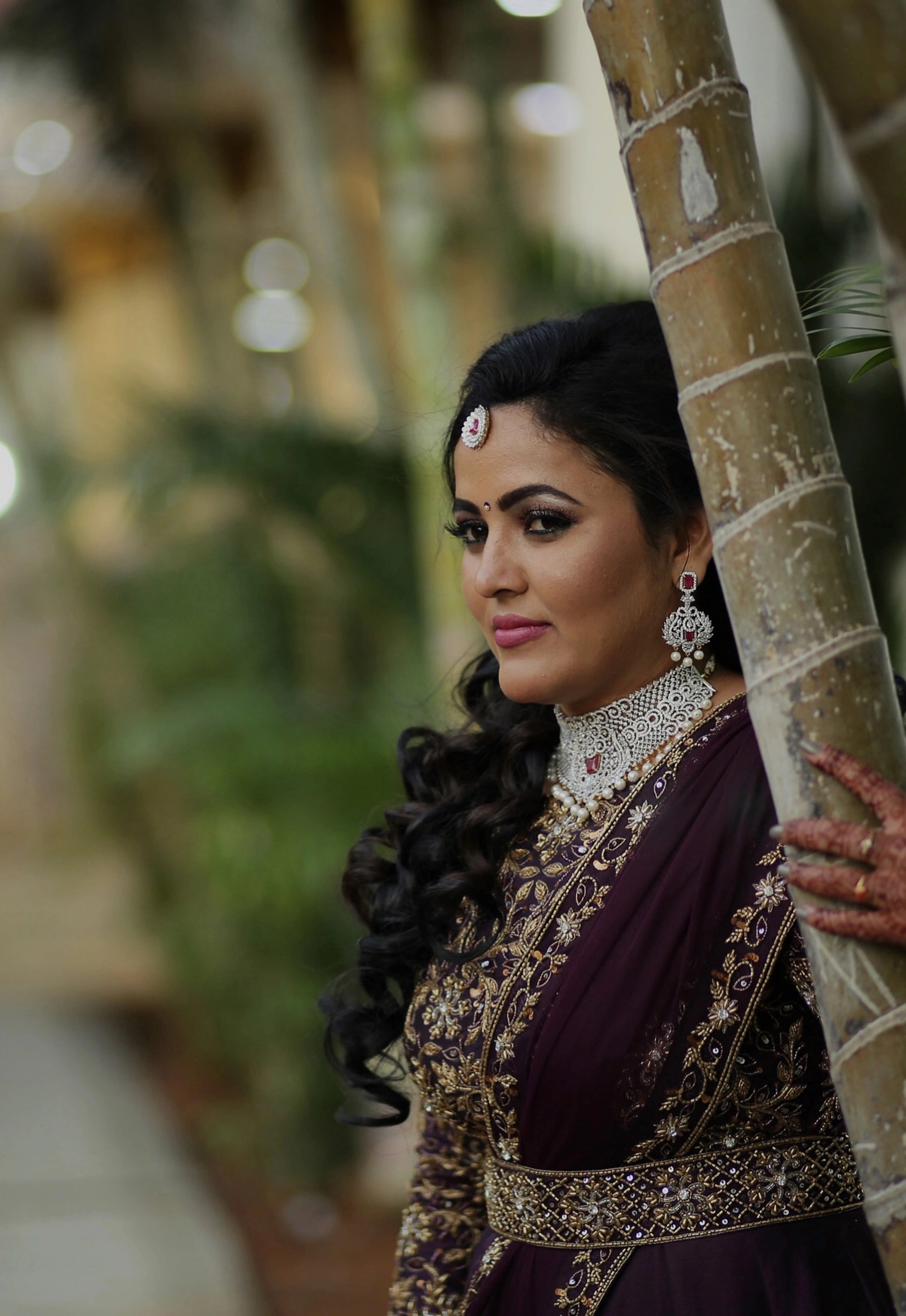 Bride Deepika posing again in an eggplant colored raw silk draped gown with belt intricately embellished with cutdana, sequins, stones and beads by team Archana Karthick.