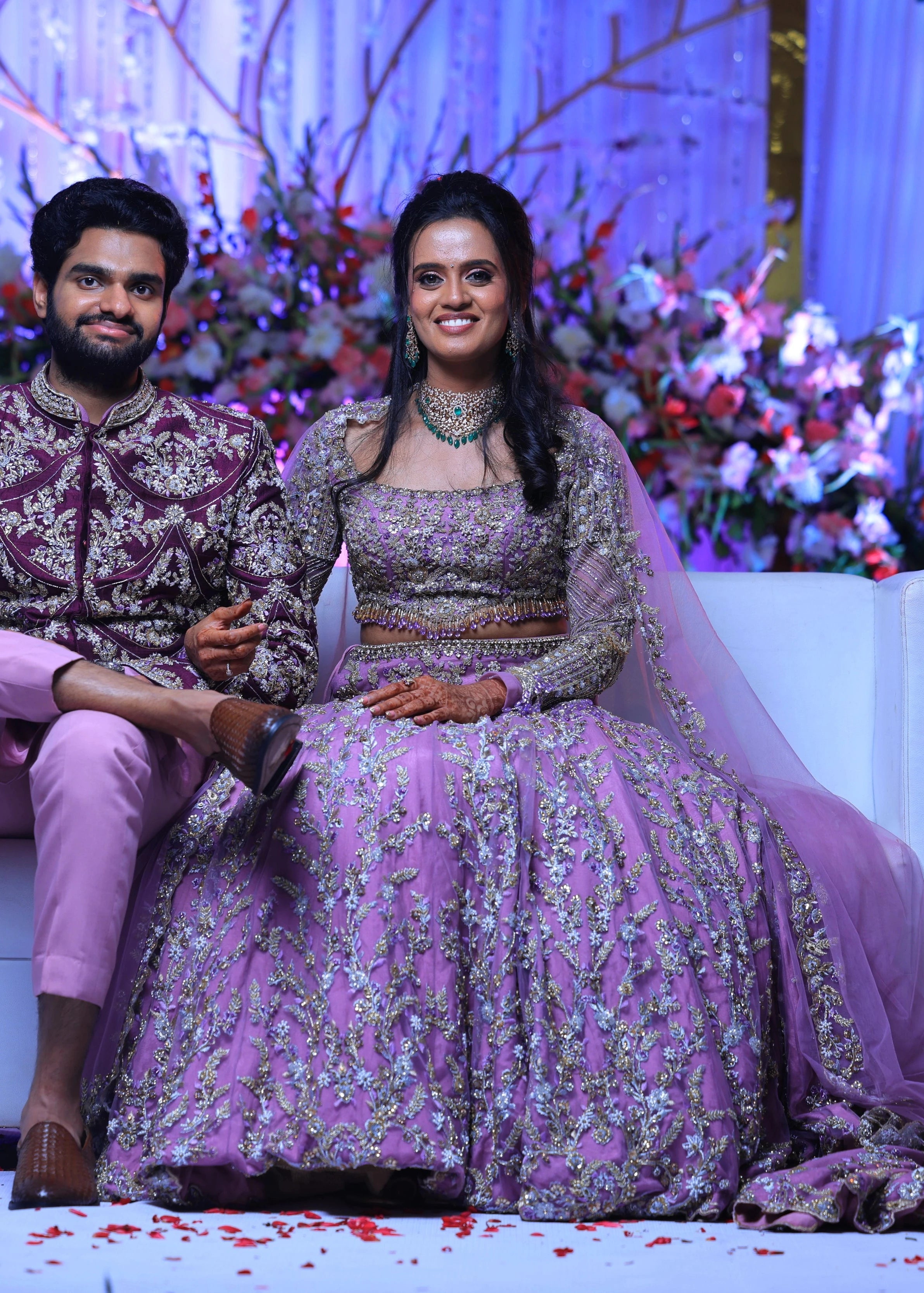 Bride Deepika smiling with groom in lavender raw silk lehenga, intricately handcrafted with sequins, cutdana, beads, crystals, rhinestones and zardozi by team Archana Karthick.
