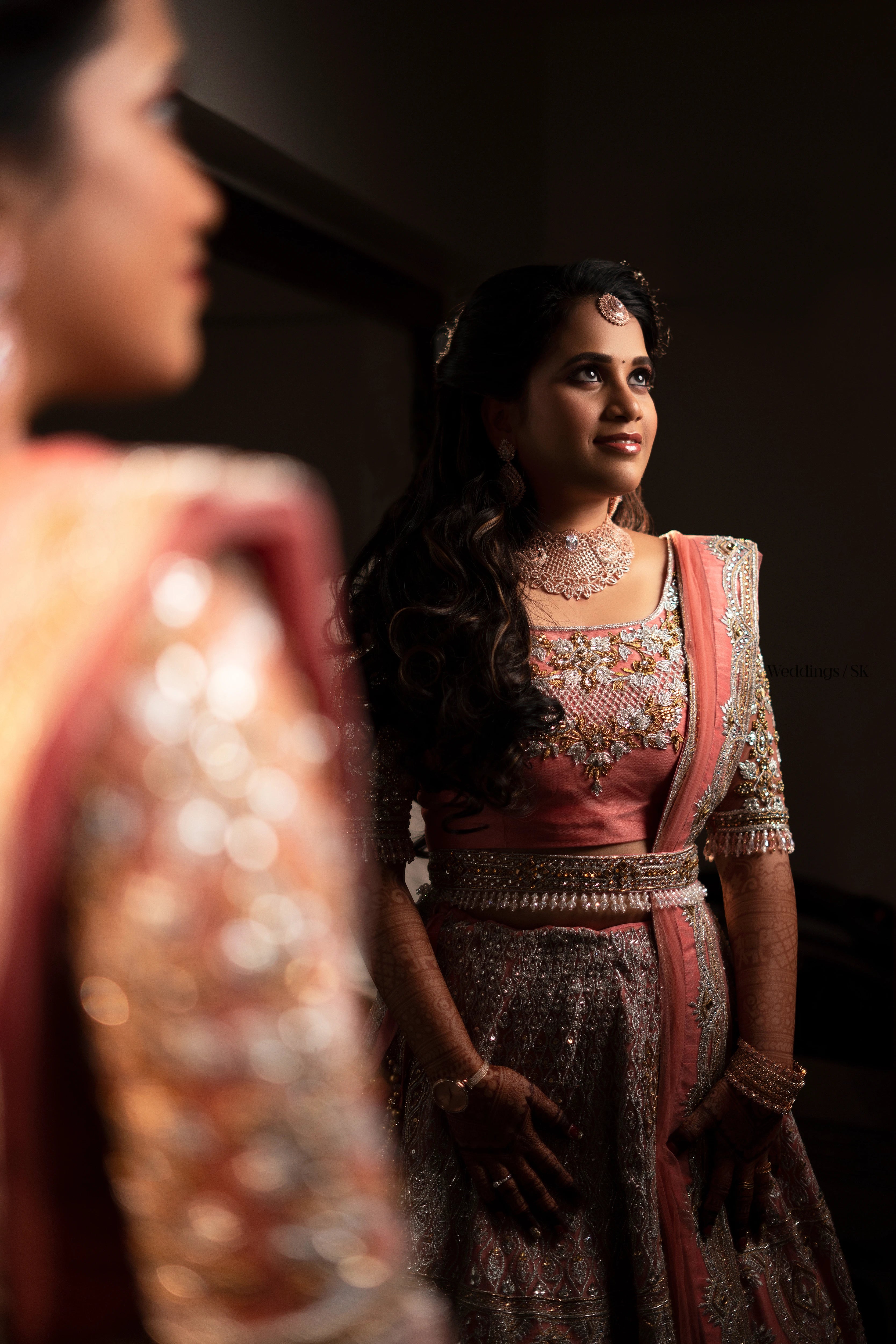 Bride Divya Gopinath from Portland, USA posing for photo in a pink peach tulle lehenga, handcrafted team Archana Karthick.
