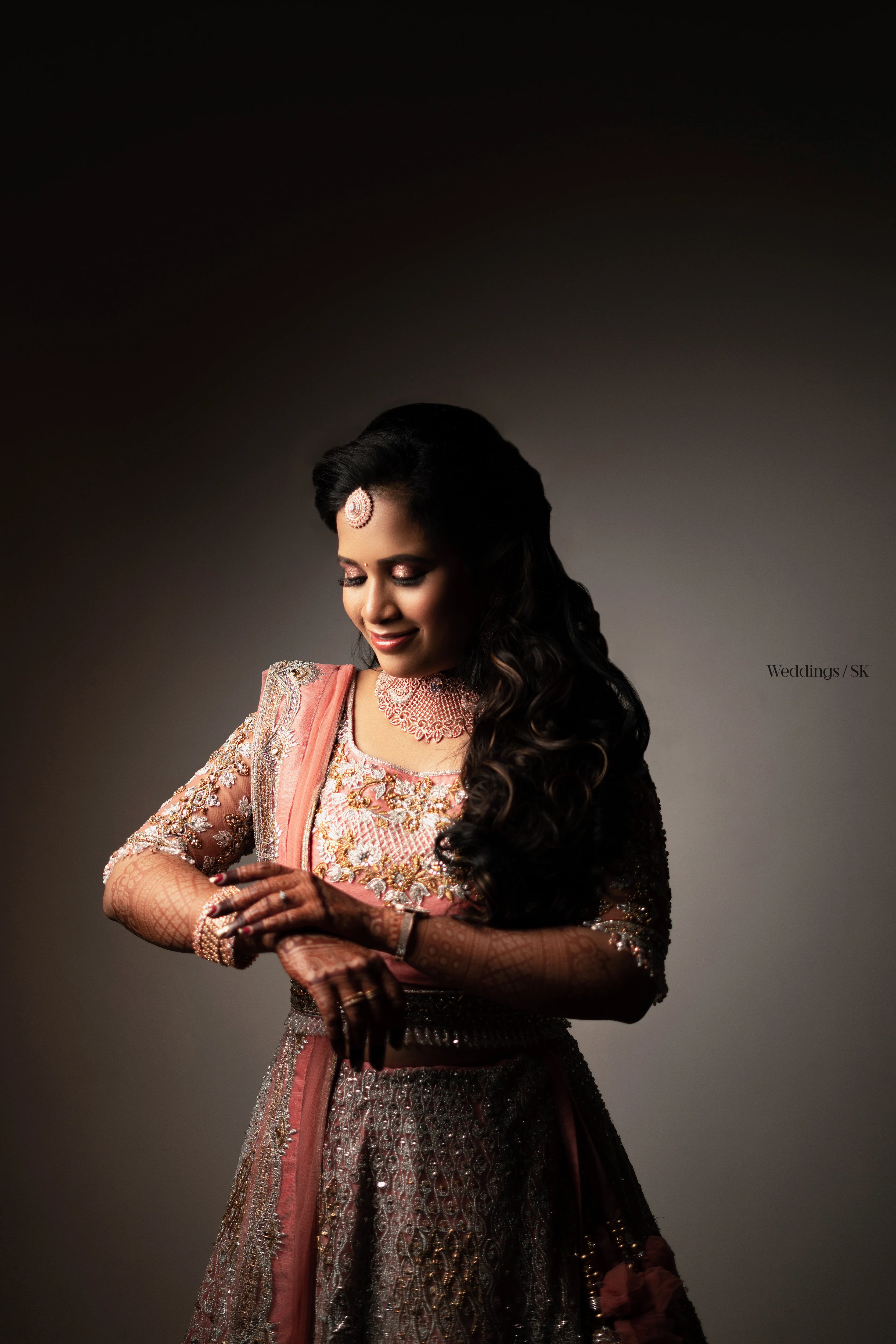 Bride Divya Gopinath from Portland, USA posing for photoshoot in a pink peach tulle lehenga, handcrafted team Archana Karthick.