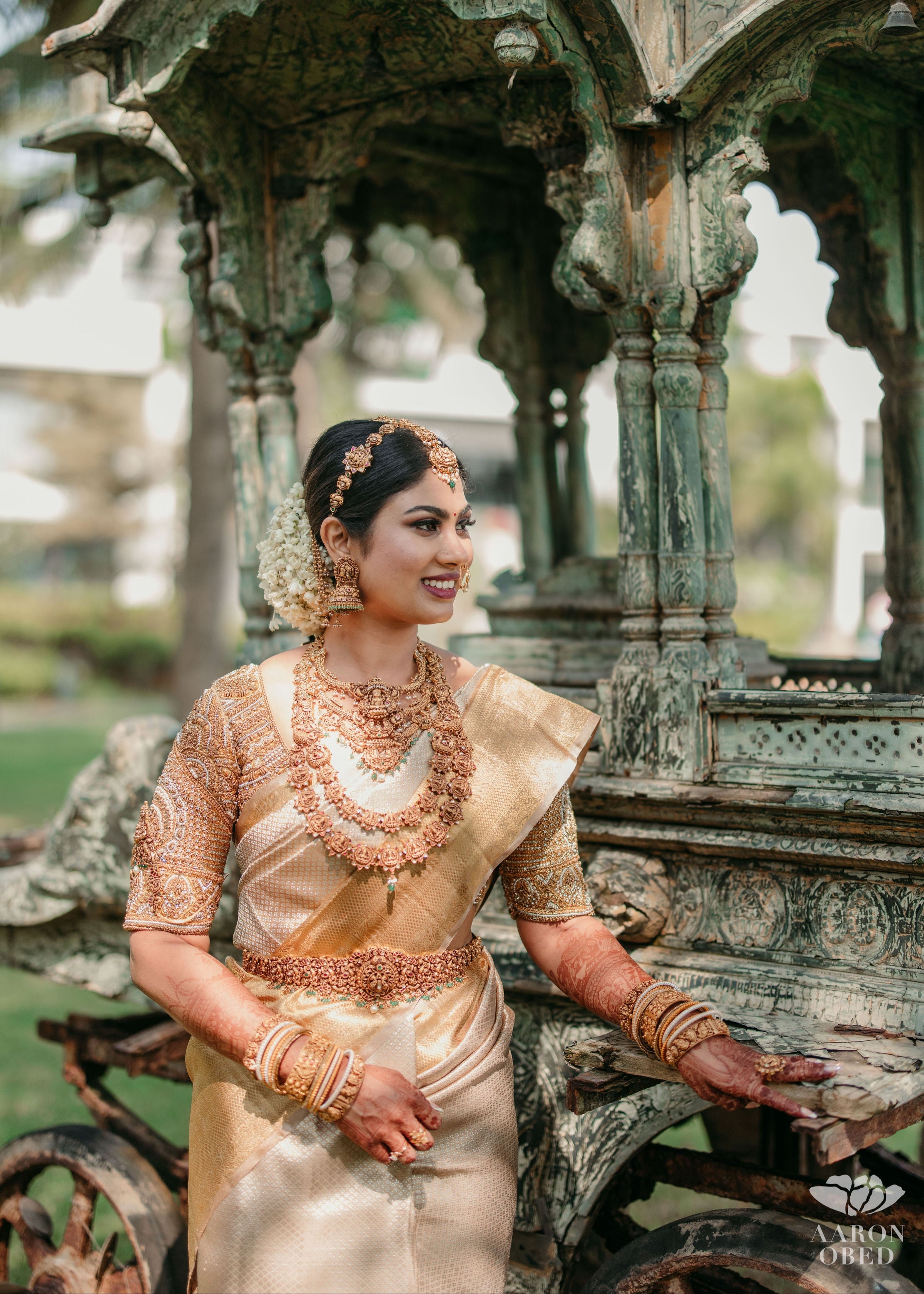 Bride Divya posing for photo in a gold silk blouse handcrafted by team Archana Karthick.
