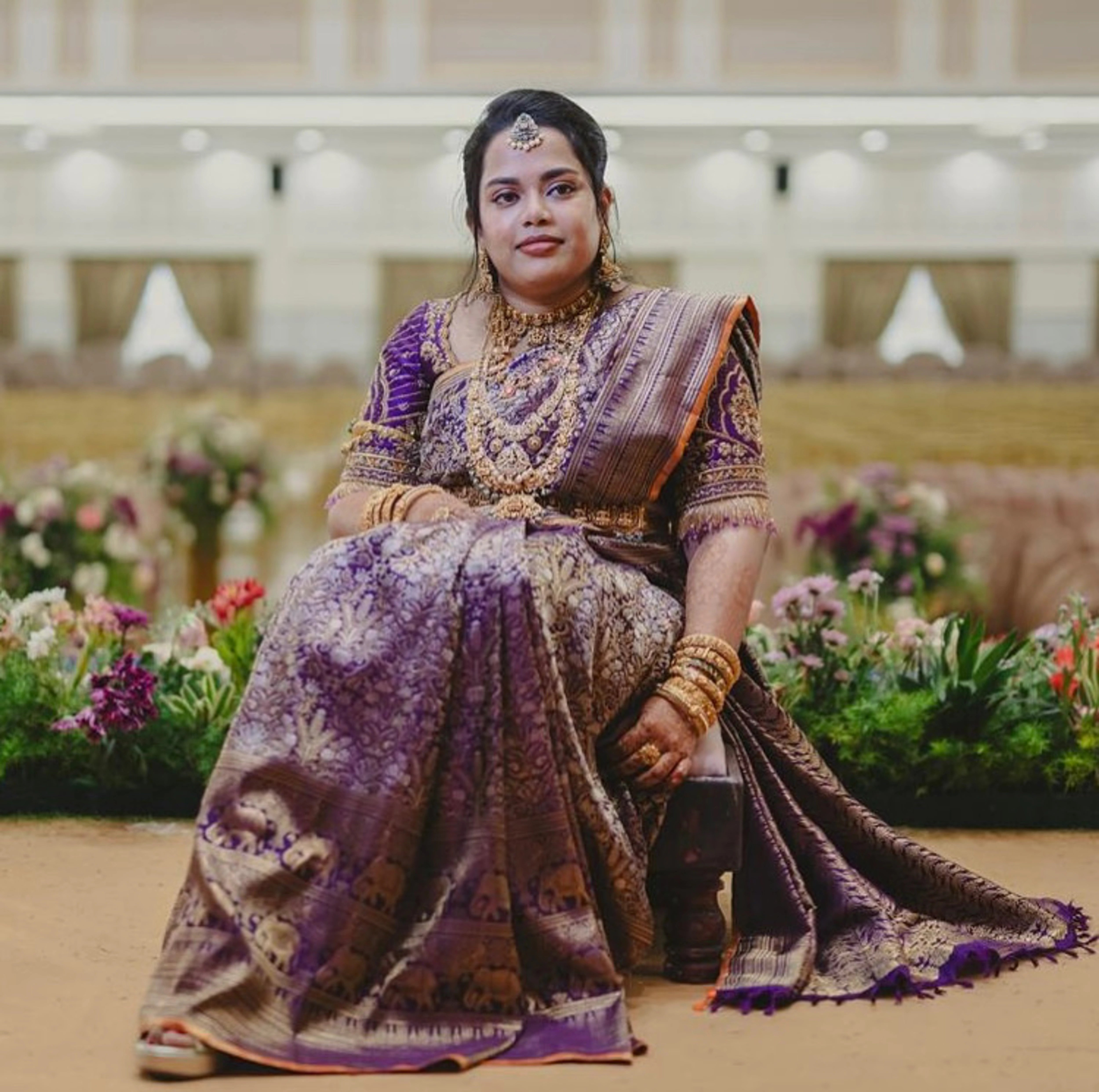 Bride Gayathri posing for photoshoot in a purple silk blouse by team Archana Karthick.