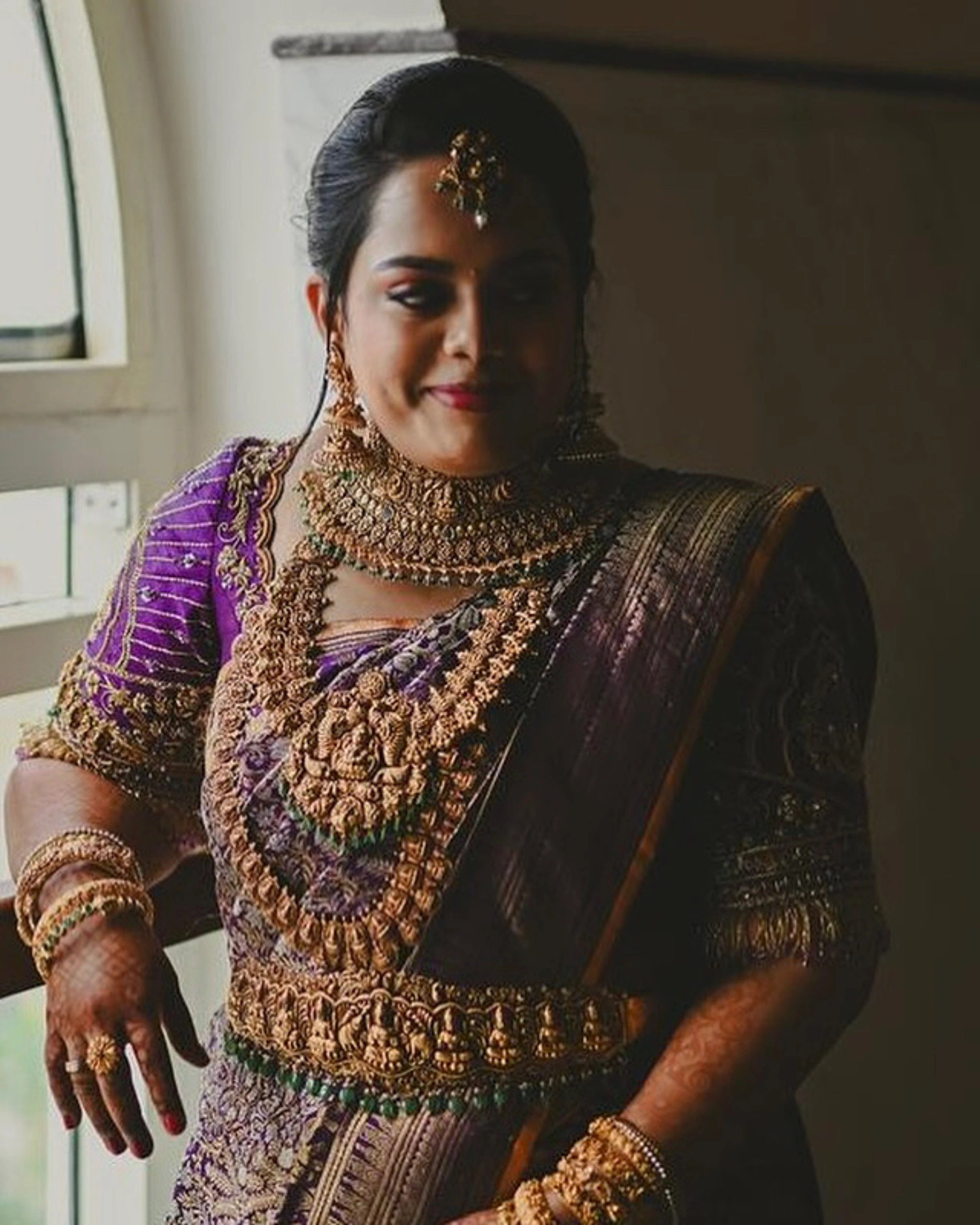 Bride Gayathri smiling in a purple silk blouse by team Archana Karthick.
