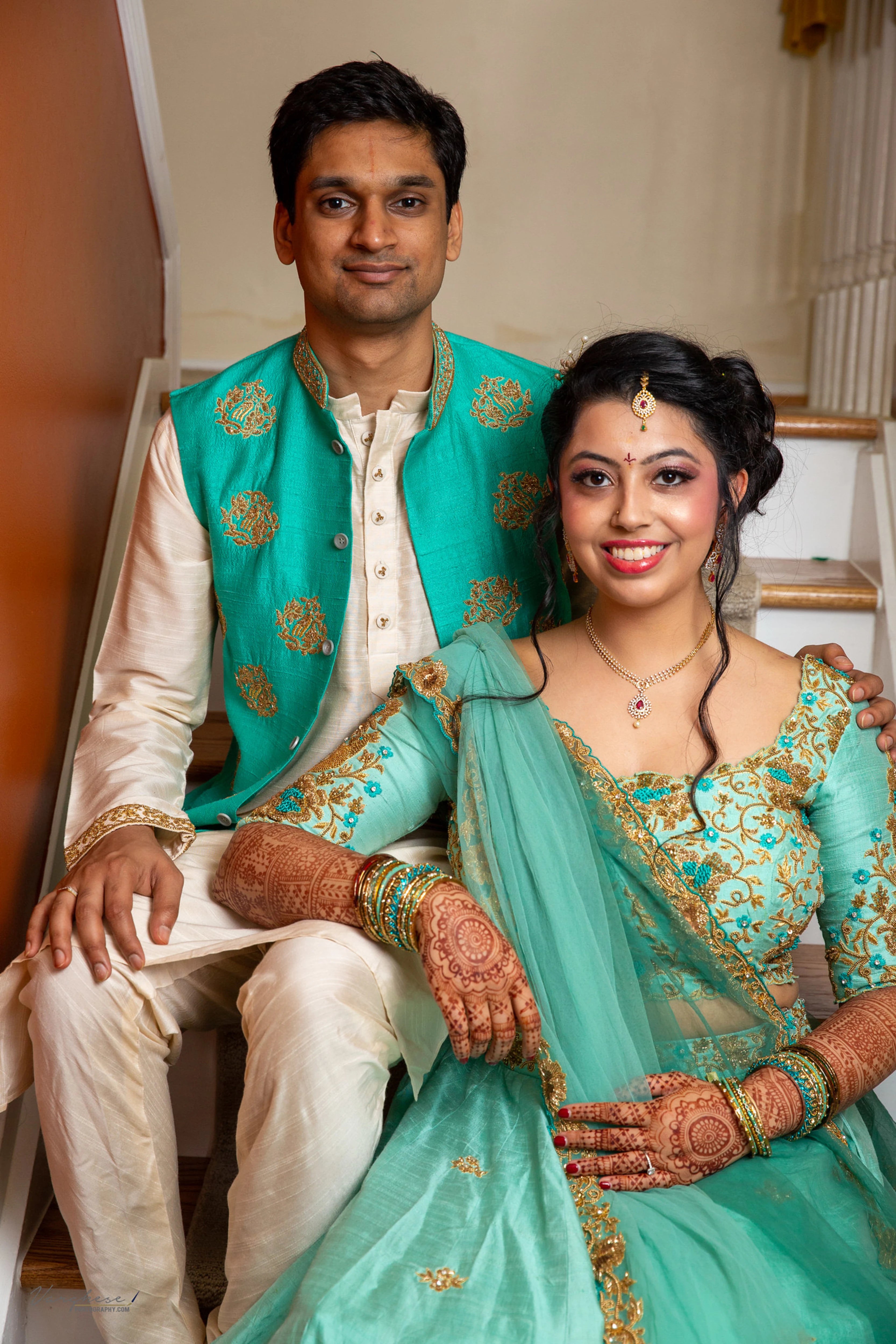 Bride & Groom from Michigan, USA, smiling in a teal raw silk lehenga and bandhgala set, handcrafted by team Archana Karthick.