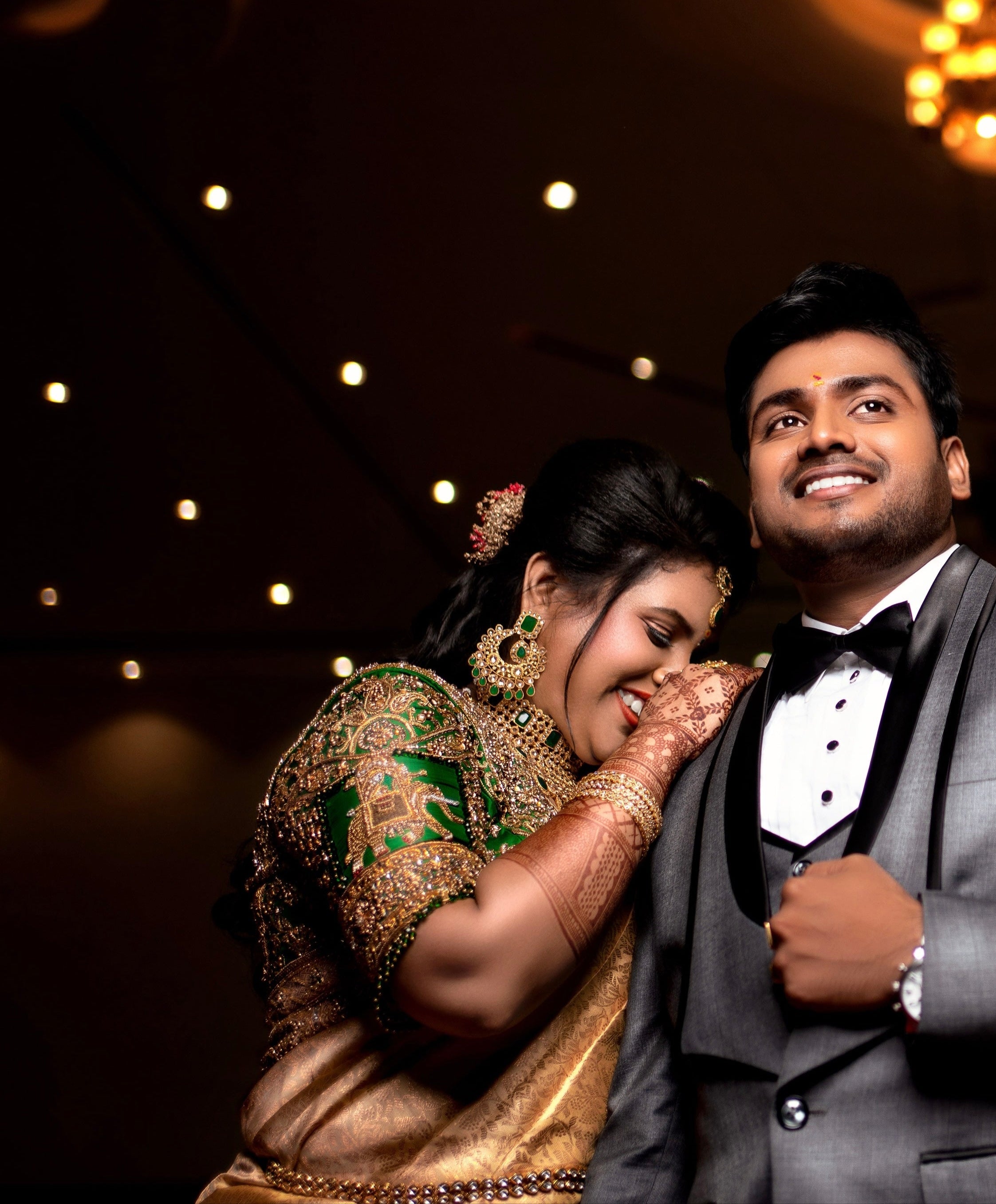 Bride Hemakiruthika from Chennai in a green raw silk blouse and gold silk saree with heavy border embellishments, designed by Archana Karthick. She is looking to her right and is posing for an intimate smile.