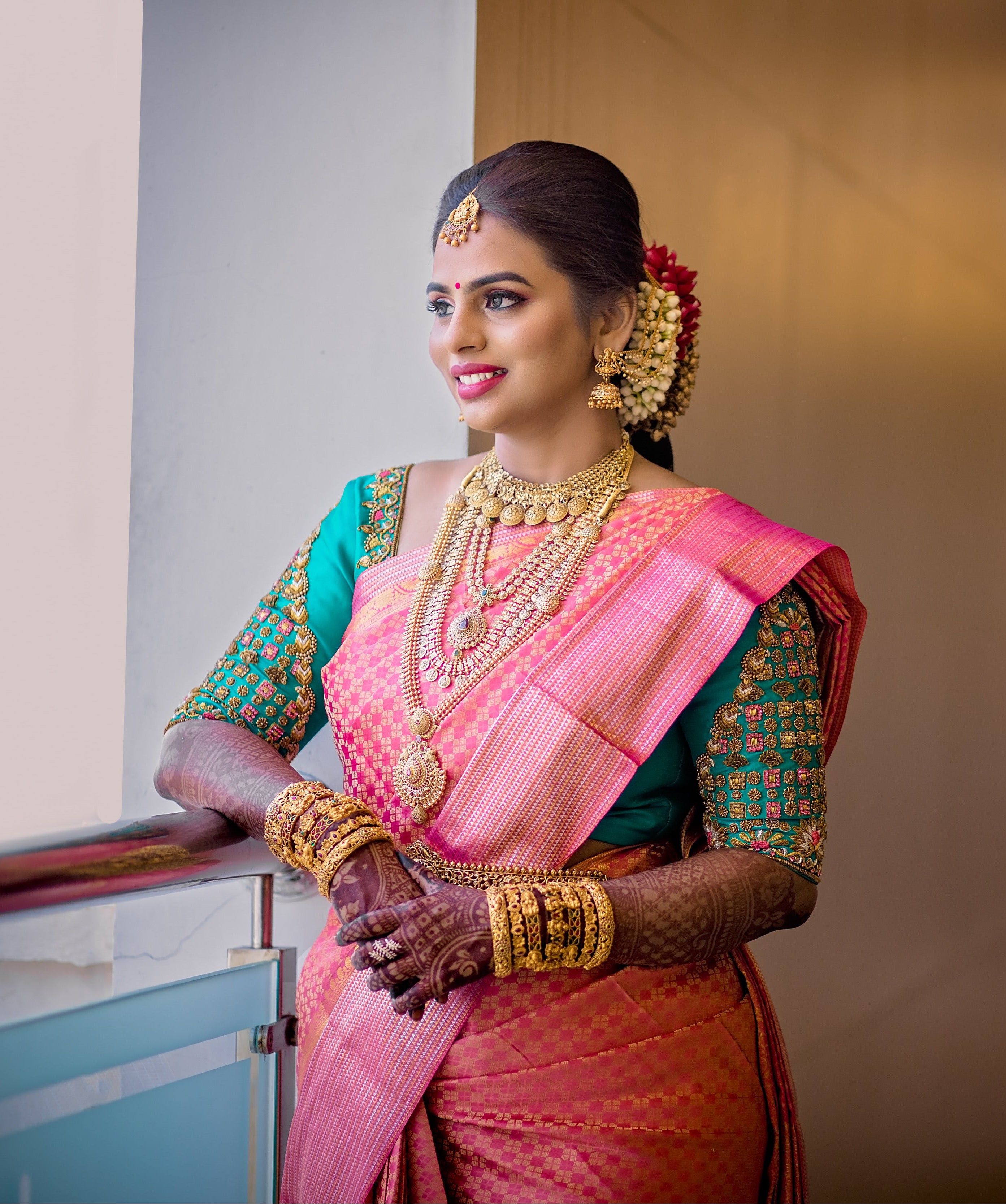Bride Kowsalya from USA in a teal raw silk blouse designed by Archana Karthick. Posing looking away from the camera.
