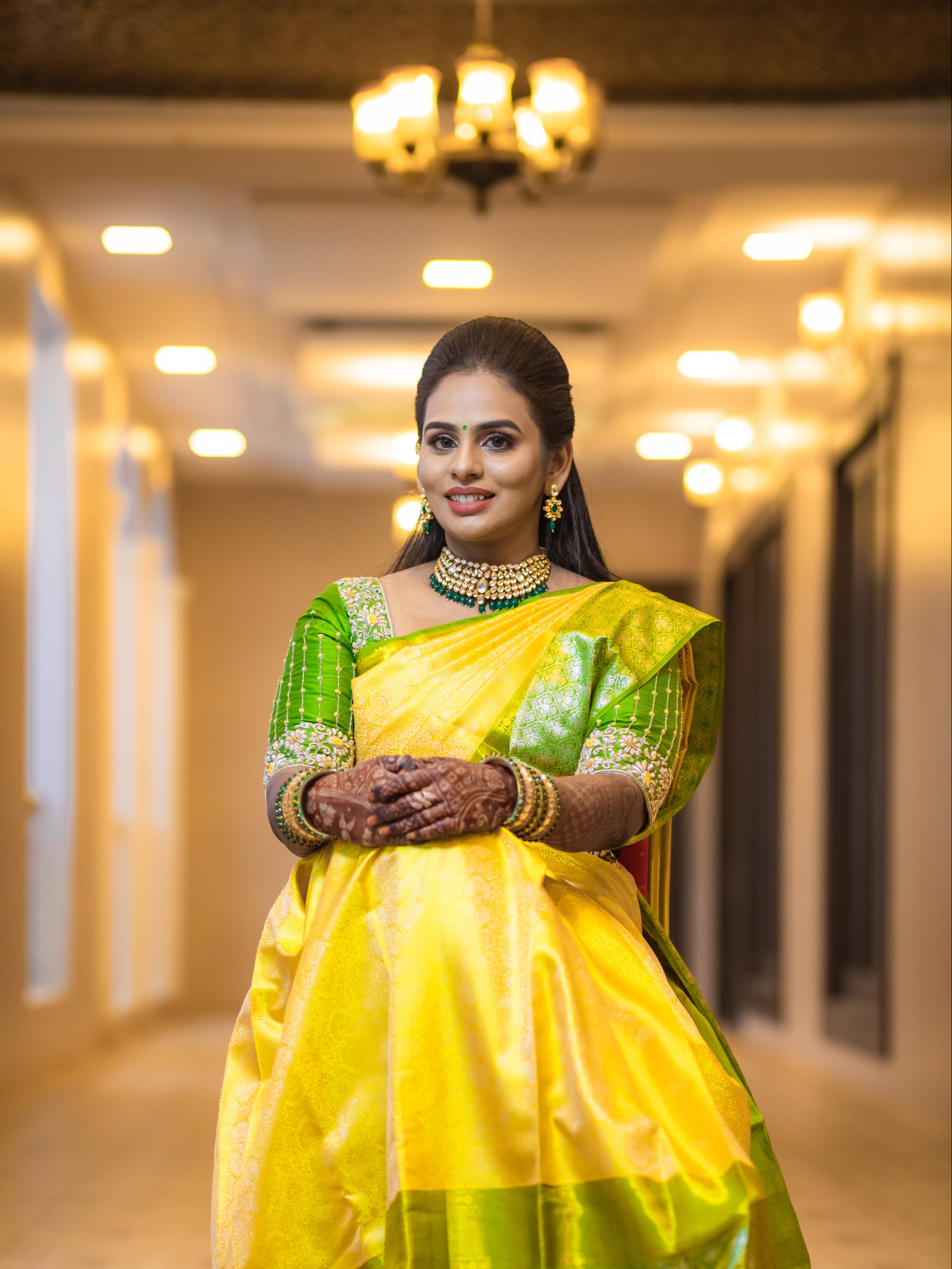 Bride Kowsalya in a handcrafted green silk blouse by Archana Karthick. Posing seated looking straight at the camera.