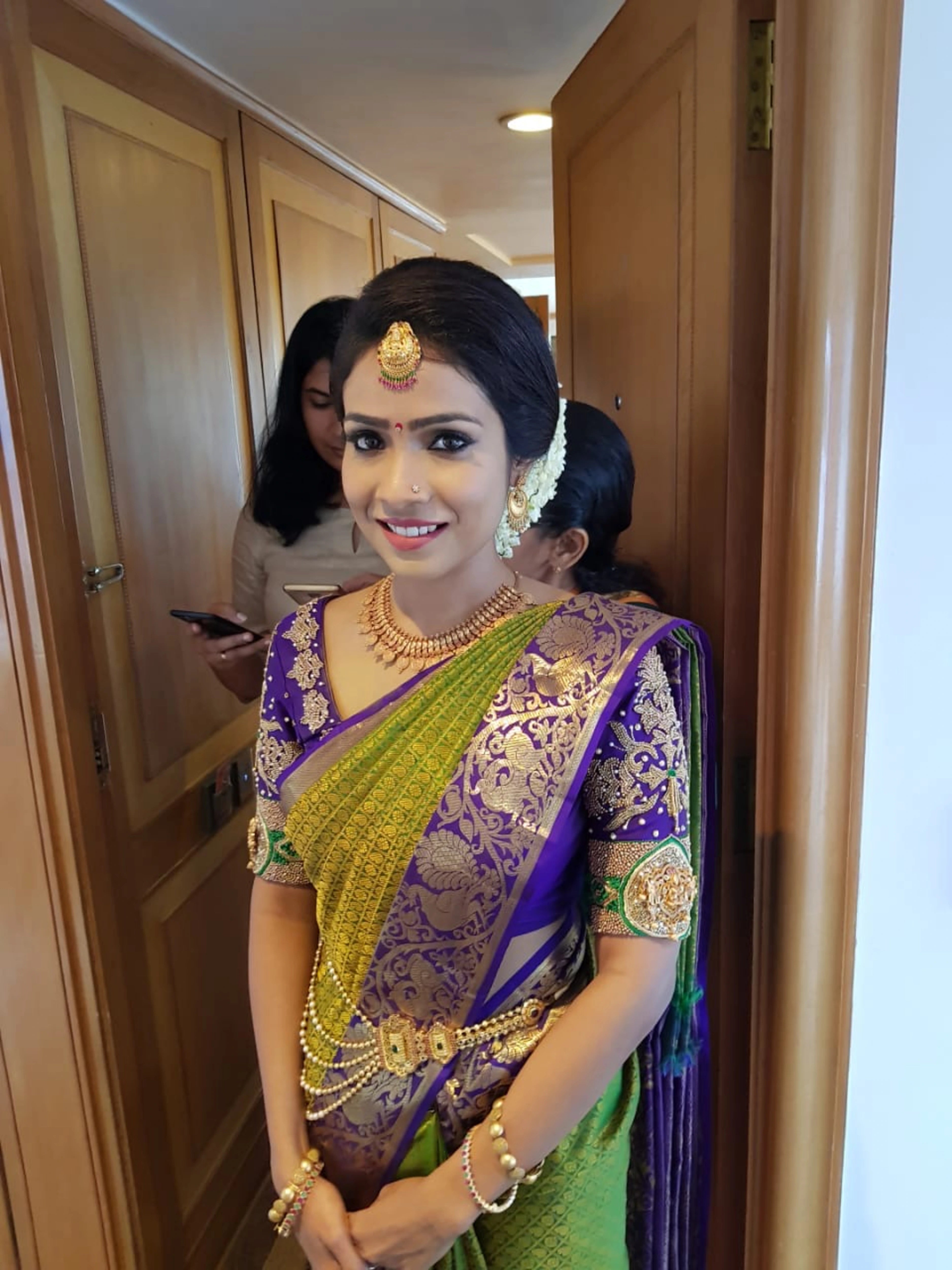 Bride Krishnapriya from Chennai smiling in a blue silk blouse handcrafted intricately with beads, stones, resham and zardozi by team Archana Karthick.