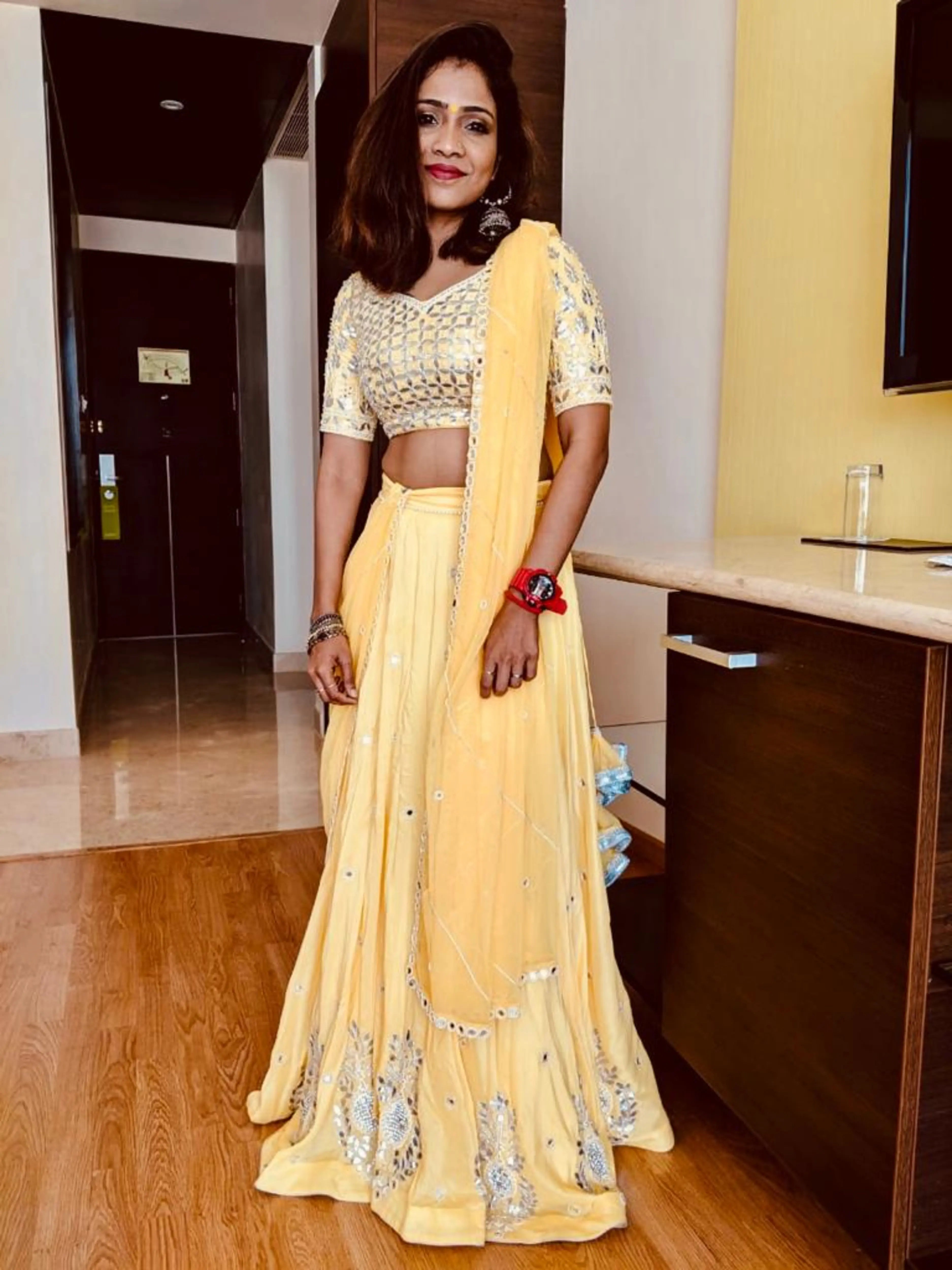 Bride Krishnapriya posing in a yellow lehenga designed by Archana Karthick.