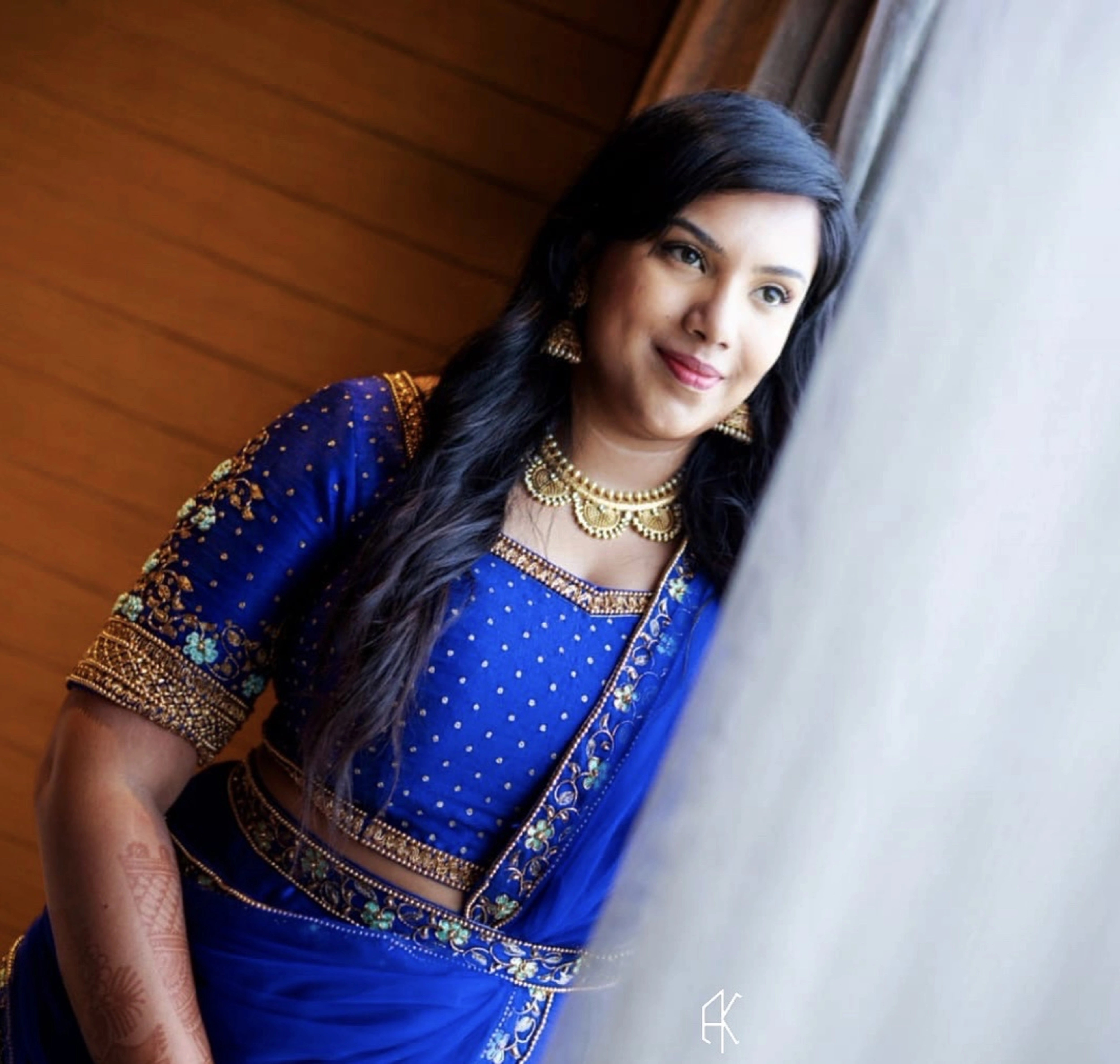 Bride Madhu Loganathan from Texas, US smiling in a blue raw silk lehenga, handcrafted with sequins, cutdana, resham and zardozi by team Archana Karthick.