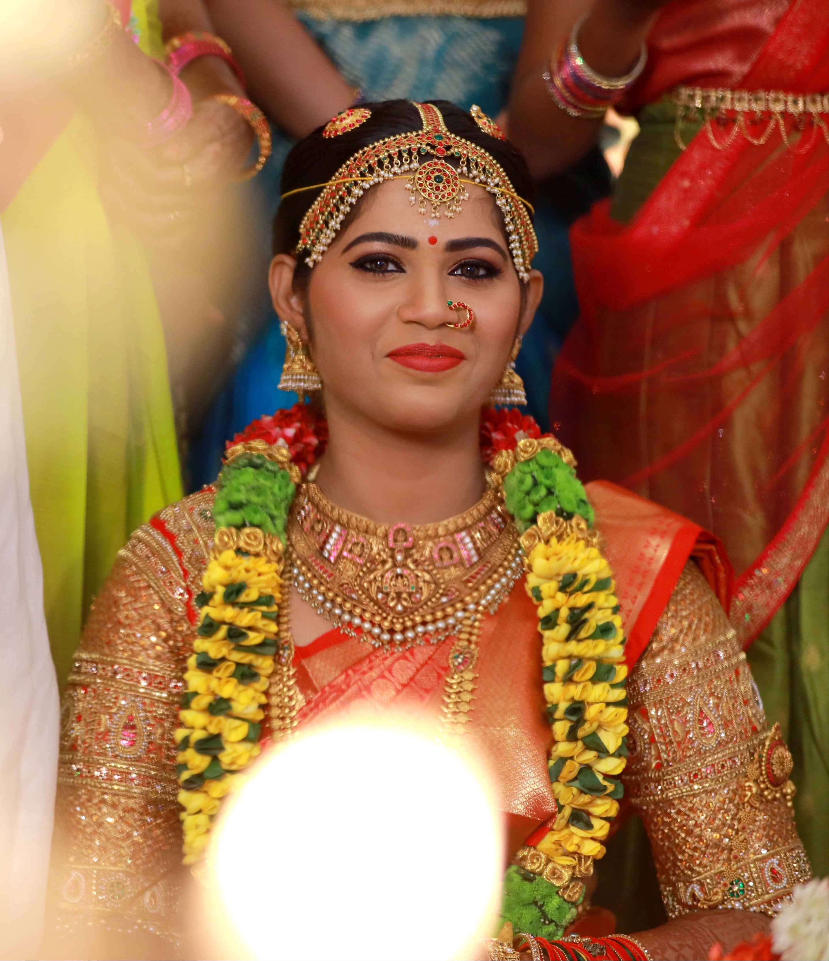 Bride Madhuvarshini in a handcrafted bridal red silk blouse designed by Archana Karthick. Looking straight at the camera.
