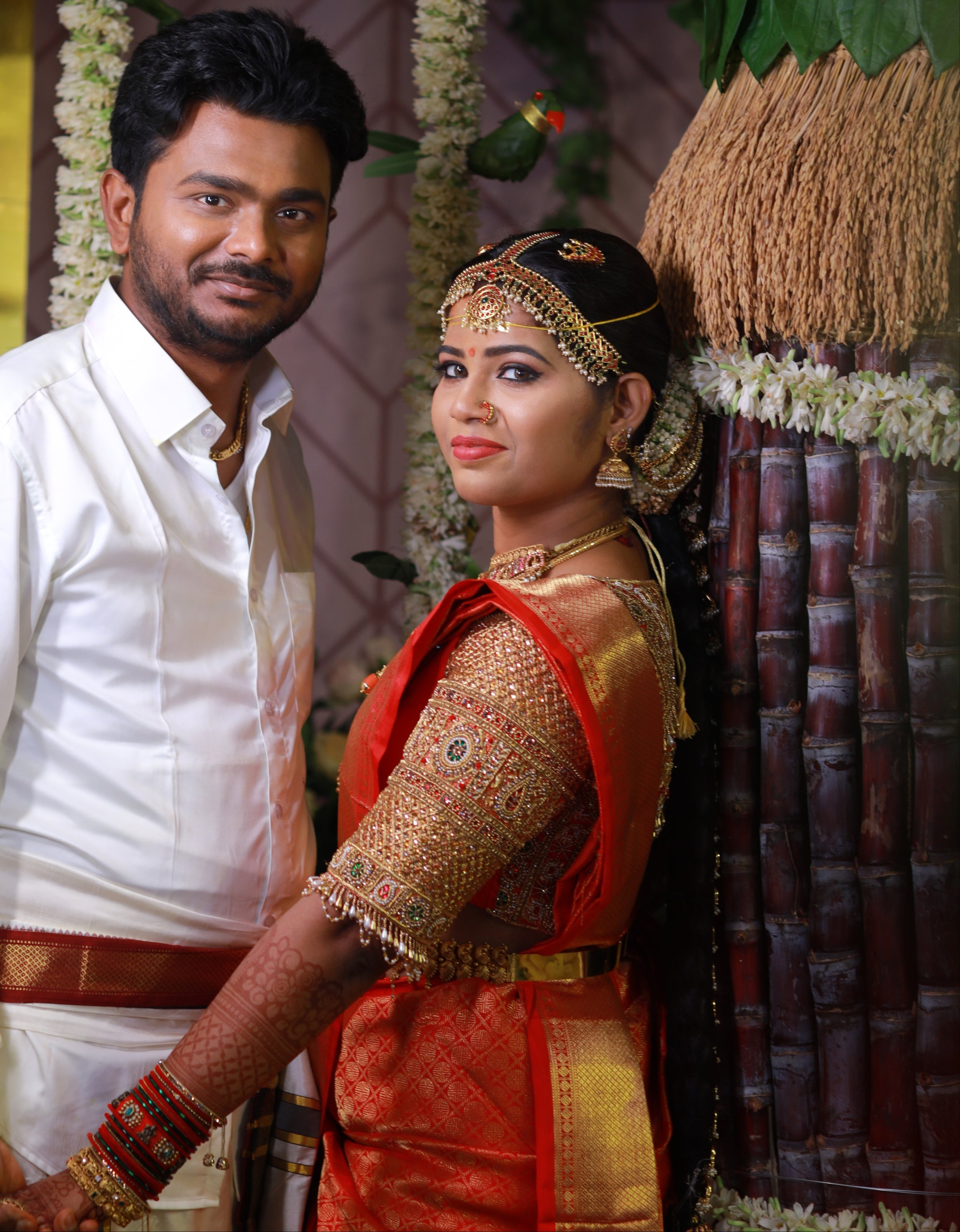 Bride Madhuvarshini in a handcrafted bridal red silk blouse designed by Archana Karthick. Posing with her groom.