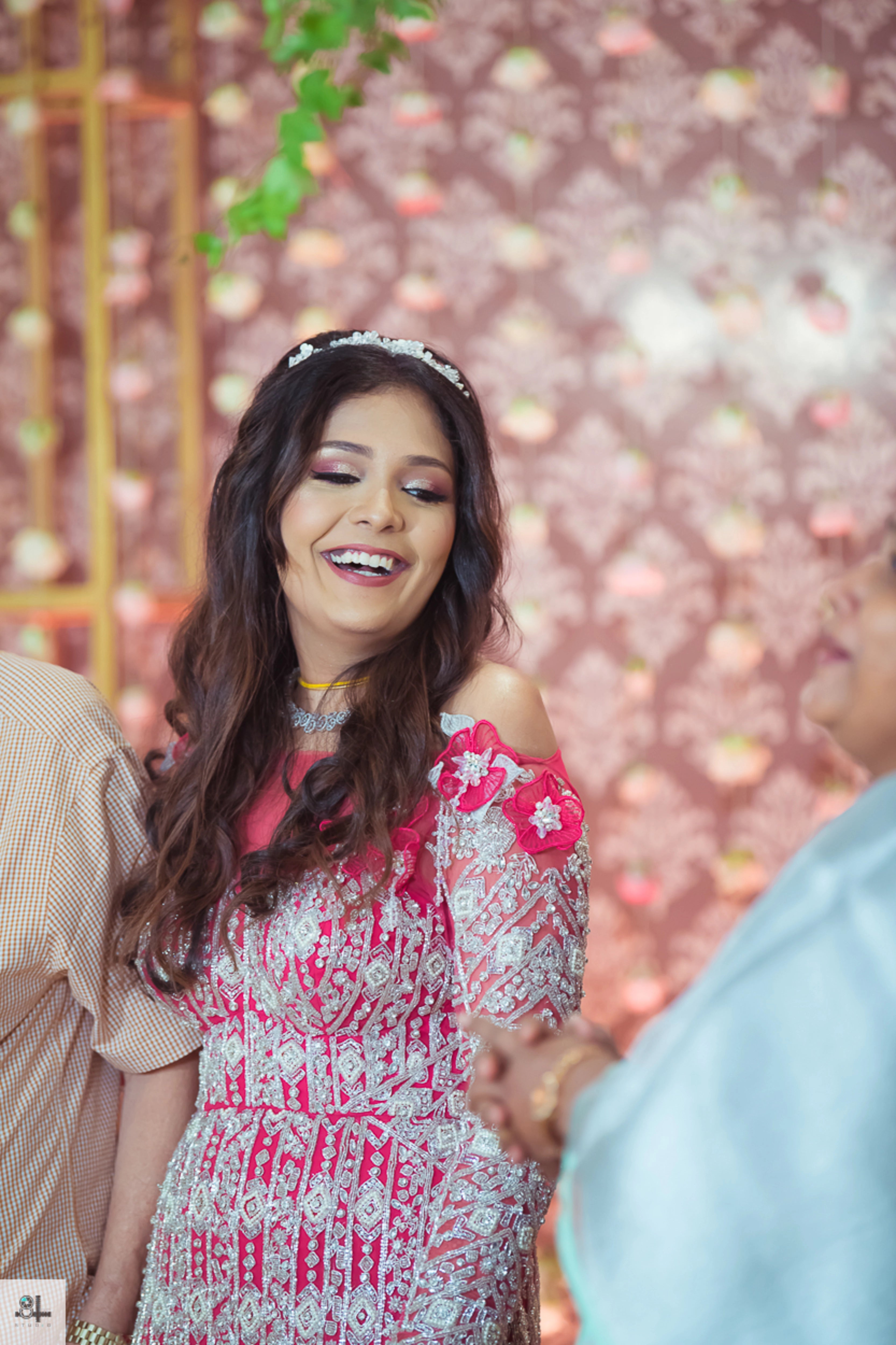 Bride Maygha Viswanath from UK smiling in a hot pink mermaid gown by team Archana Karthick.