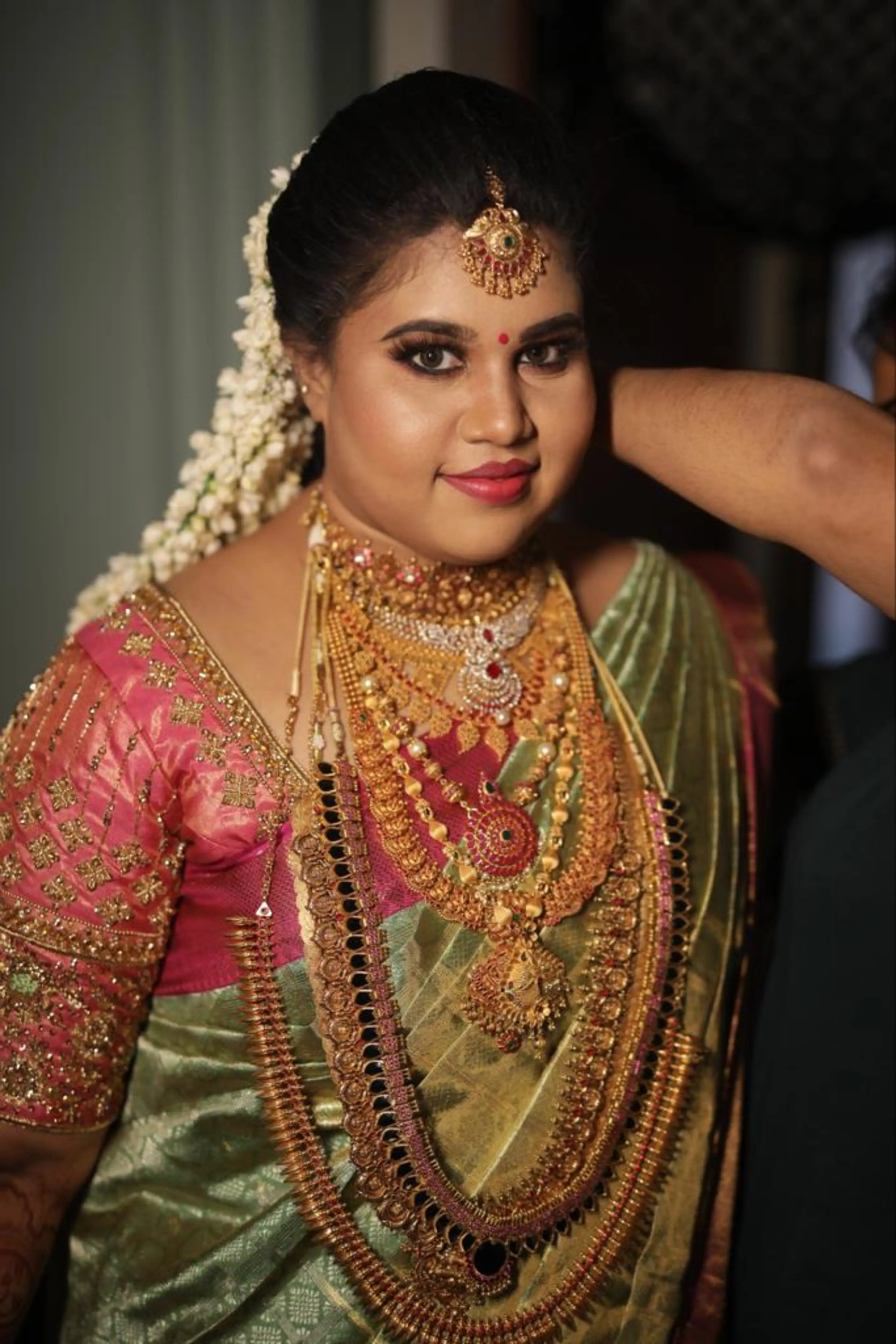 Bride Monisha from Kerala posing in a pink silk blouse by team Archana Karthick.