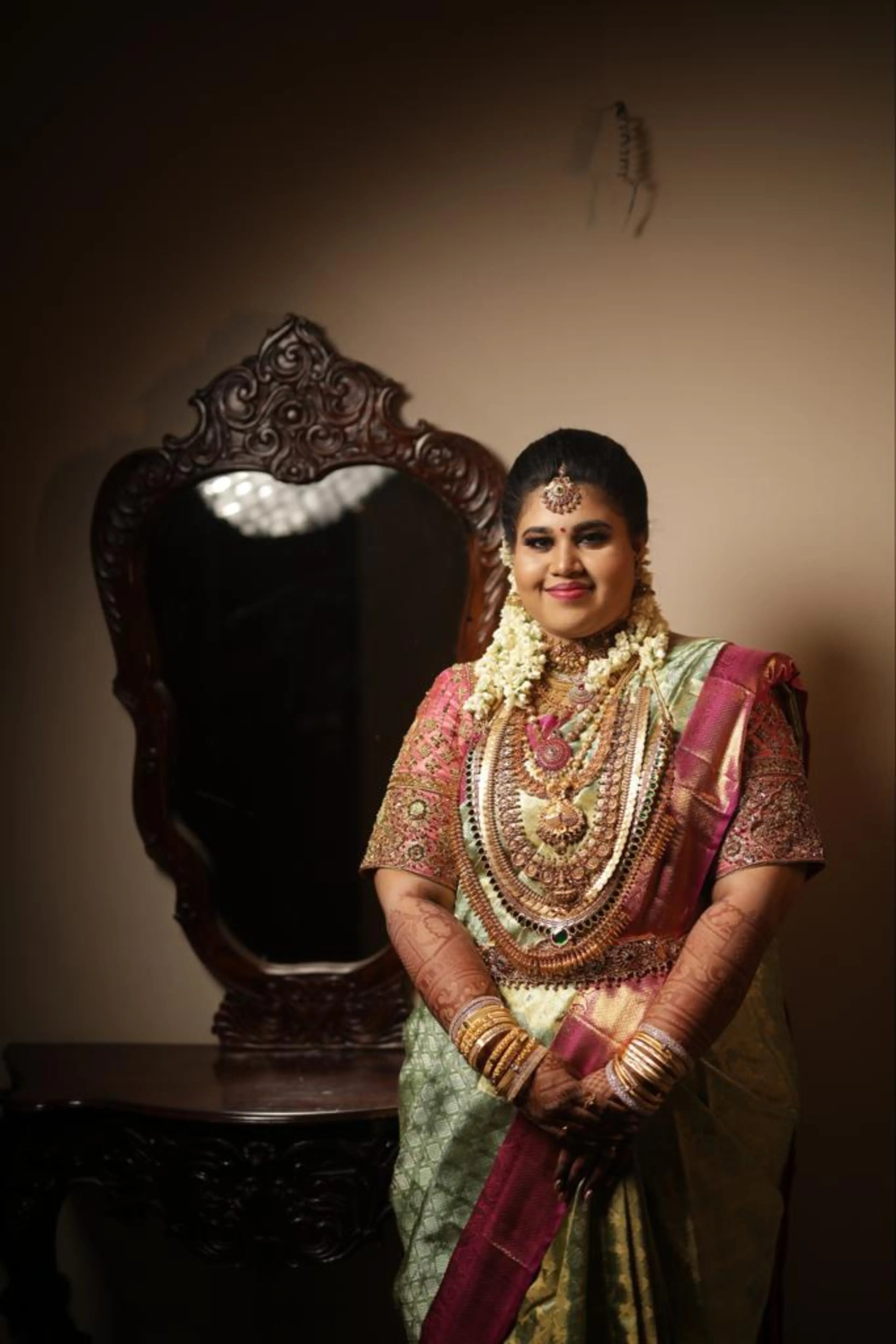 Bride Monisha from Kerala smiling in a pink silk blouse by team Archana Karthick.