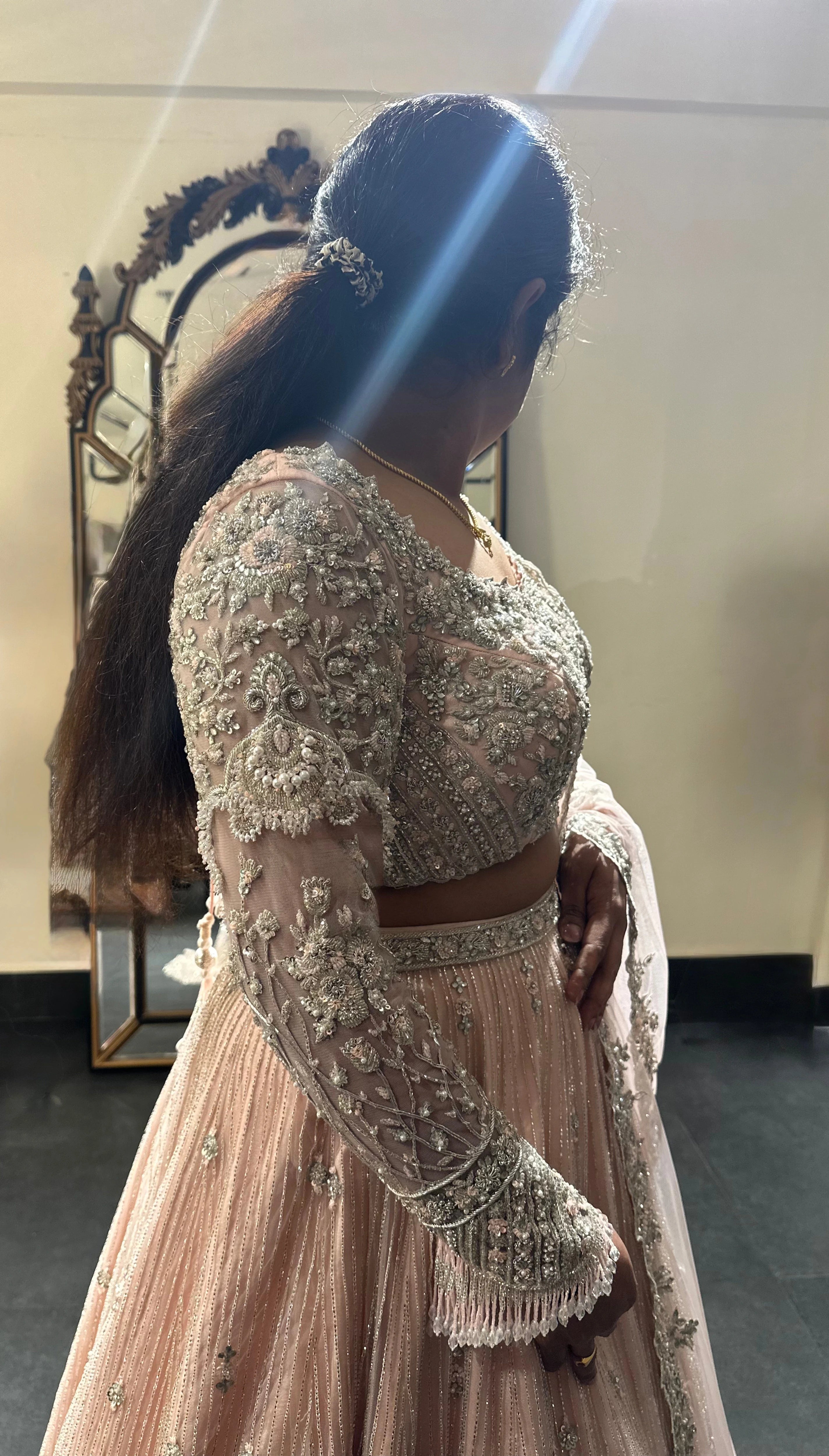 Bride Nandhini Krishnan posing in a blush tulle reception lehenga, handcrafted by team Archana Karthick.