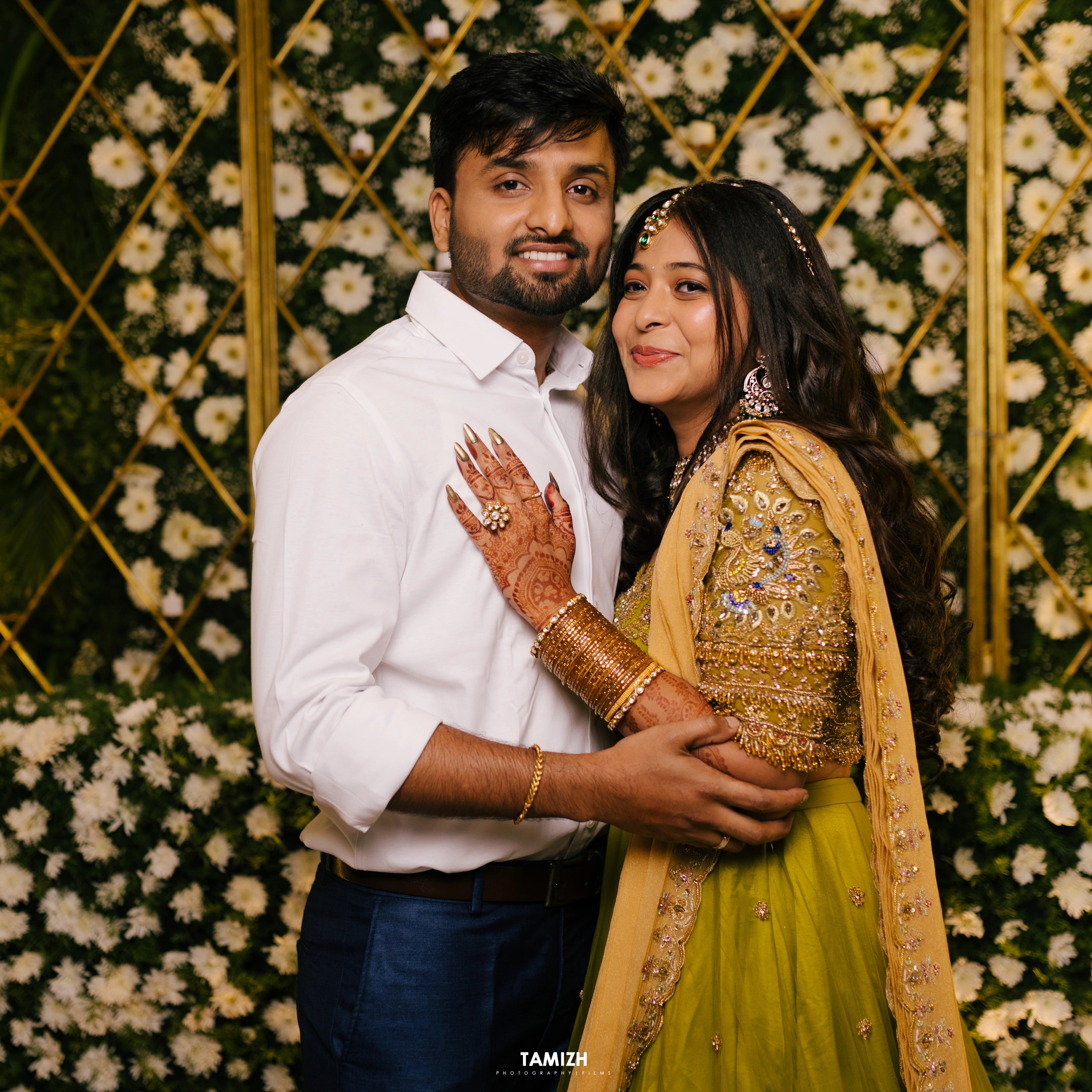 Bride Nandita posing with groom in a olive green tulle lehenga by team Archana Karthick.
