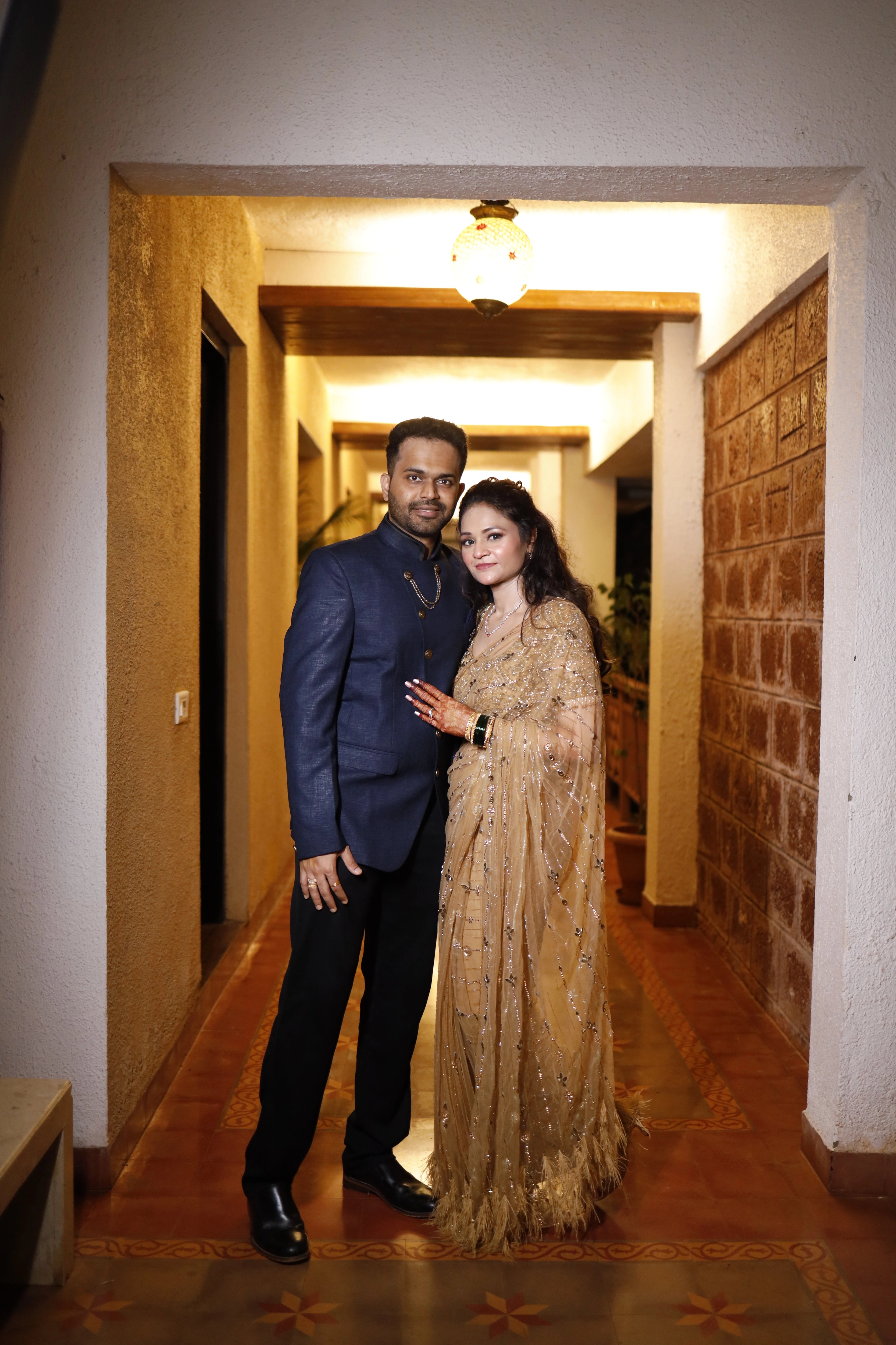 Bride Neha from Virginia posing with groom, in a golden tulle saree, handcrafted with rhinestones, zardozi, sequins, crystals, cutdana and stones by team Archana Karthick.