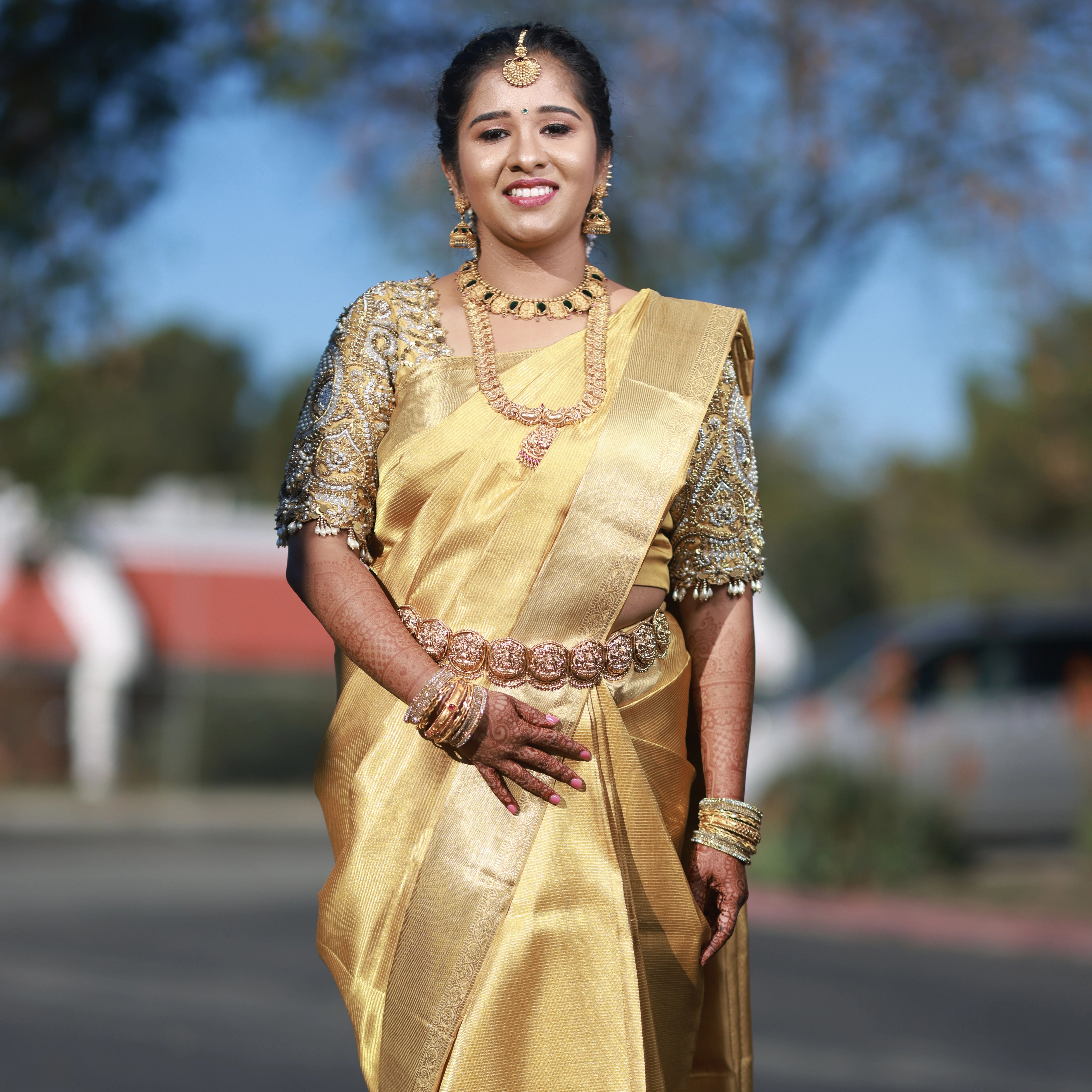 Bride Niveda posing for photo in a gold silk blouse handcrafted by team Archana Karthick.