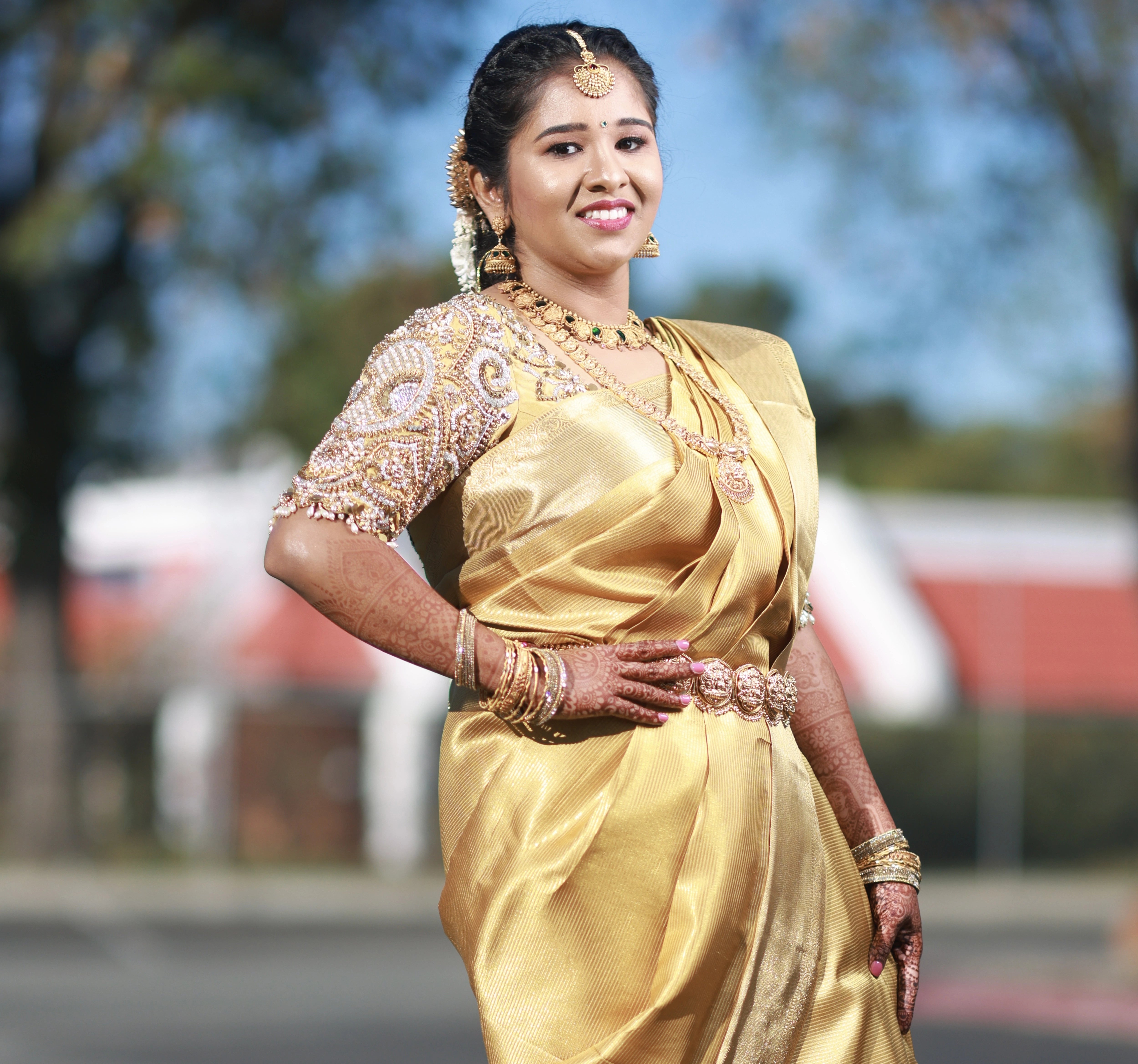 Bride Niveda posing in a gold silk blouse handcrafted by team Archana Karthick.
