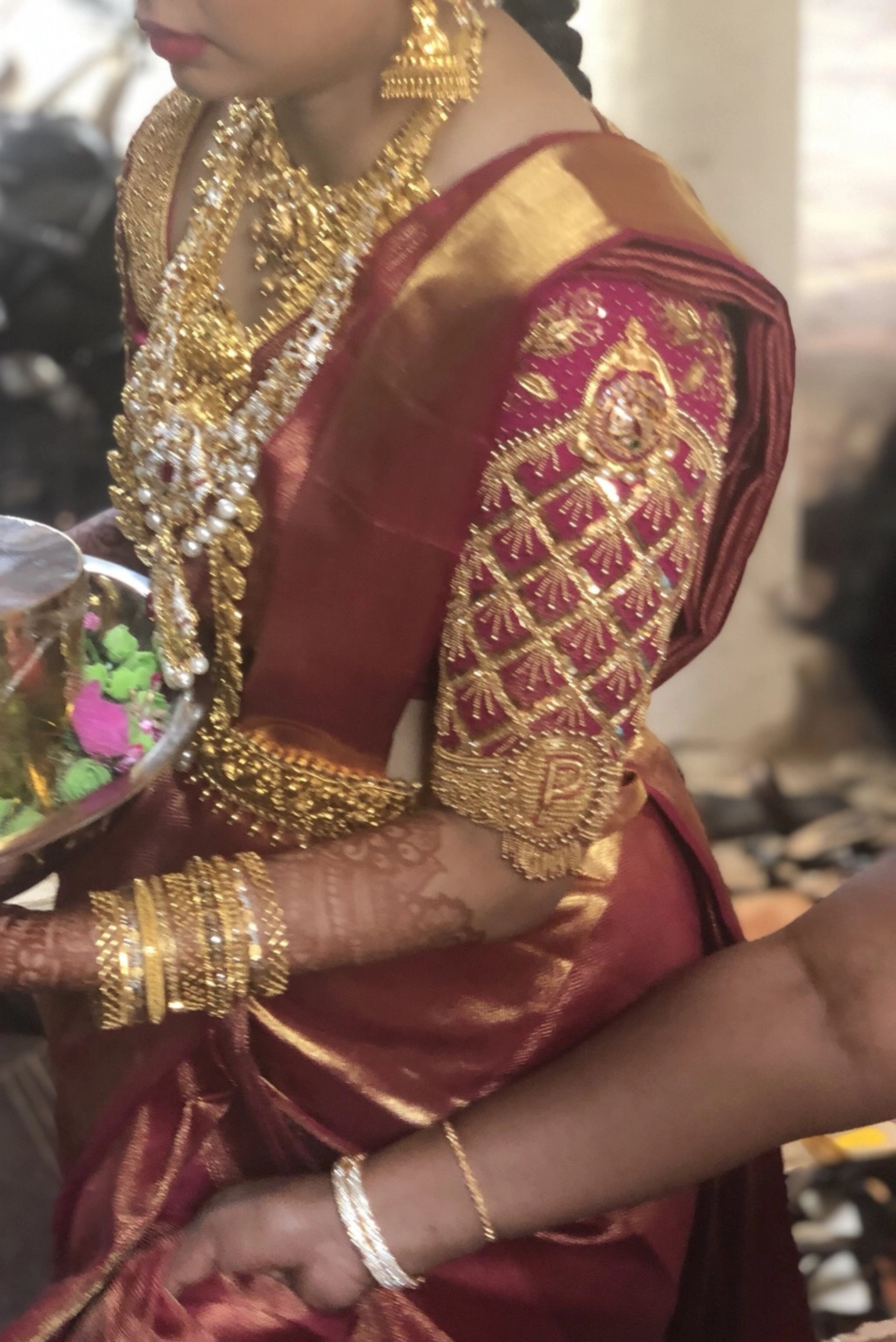 Bride Padma from Coimbatore showcasing sleeve in a red silk palanquin concept blouse intricately handcrafted with zardozi, stones, beads, sequins etc by team Archana Karthick.