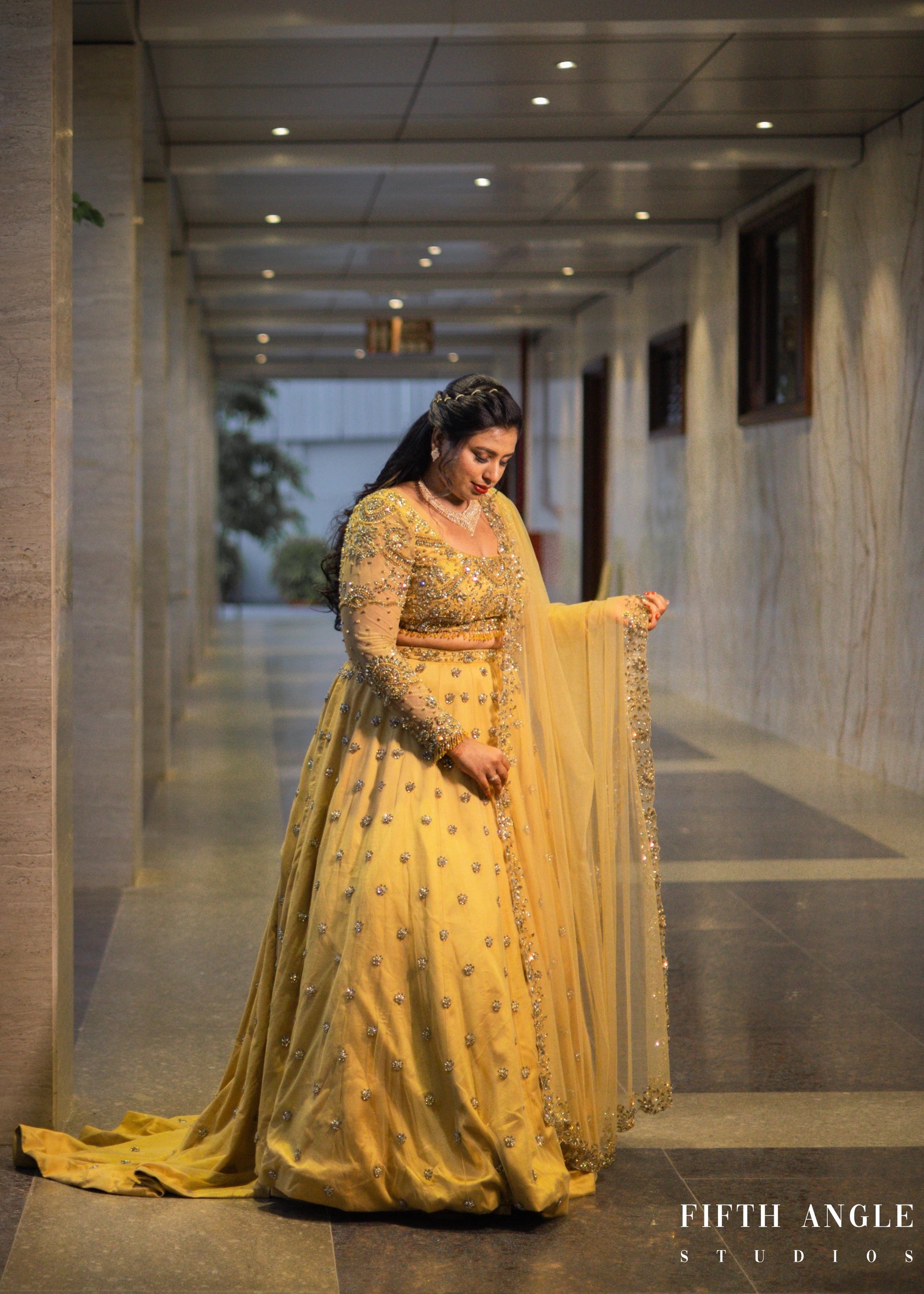 Bride Pooja Das posing for photo in a golden tulle lehenga handcrafted by team Archana Karthick.