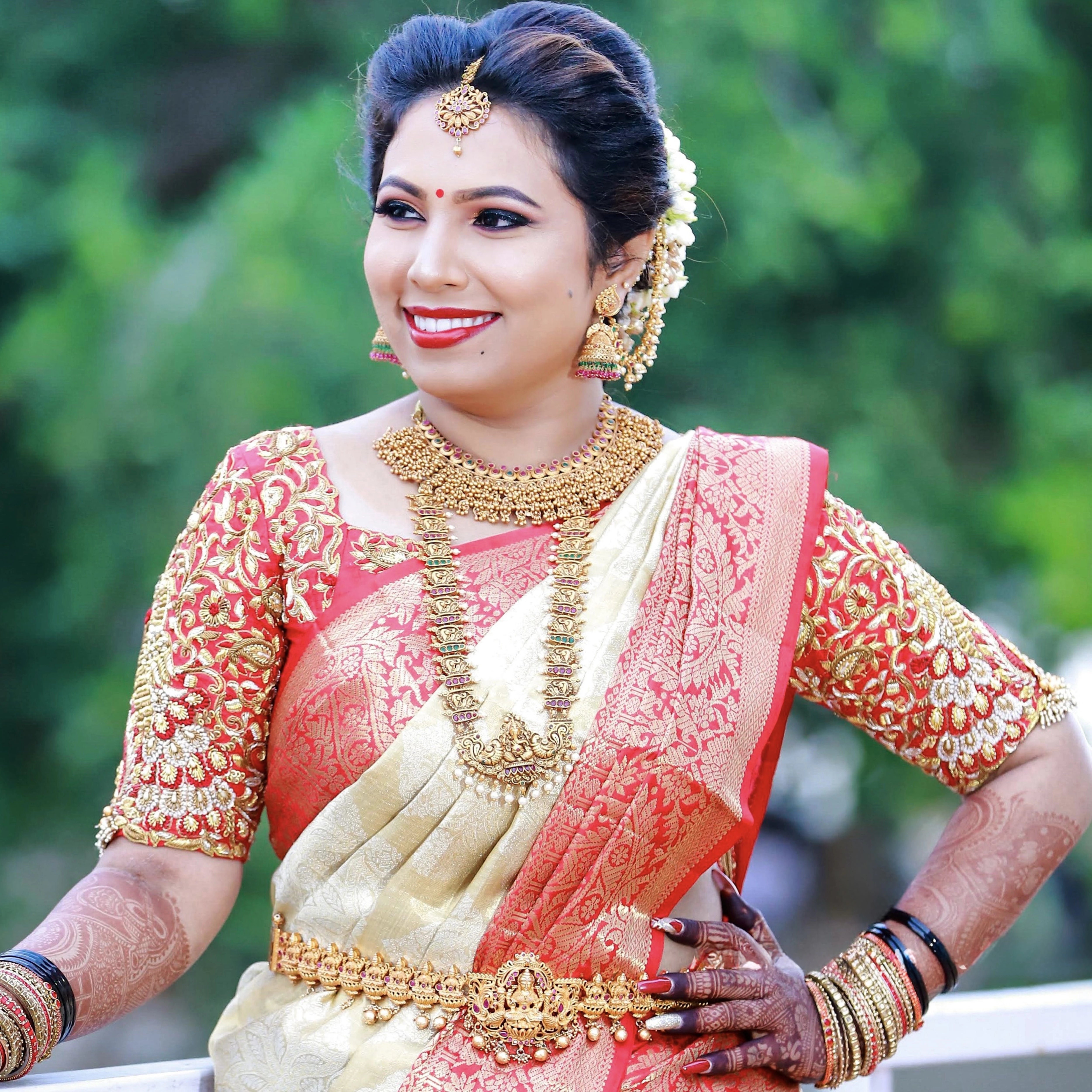 Bride Pooja from Bangalore, smiling in a red silk blouse handcrafted by team Archana Karthick.