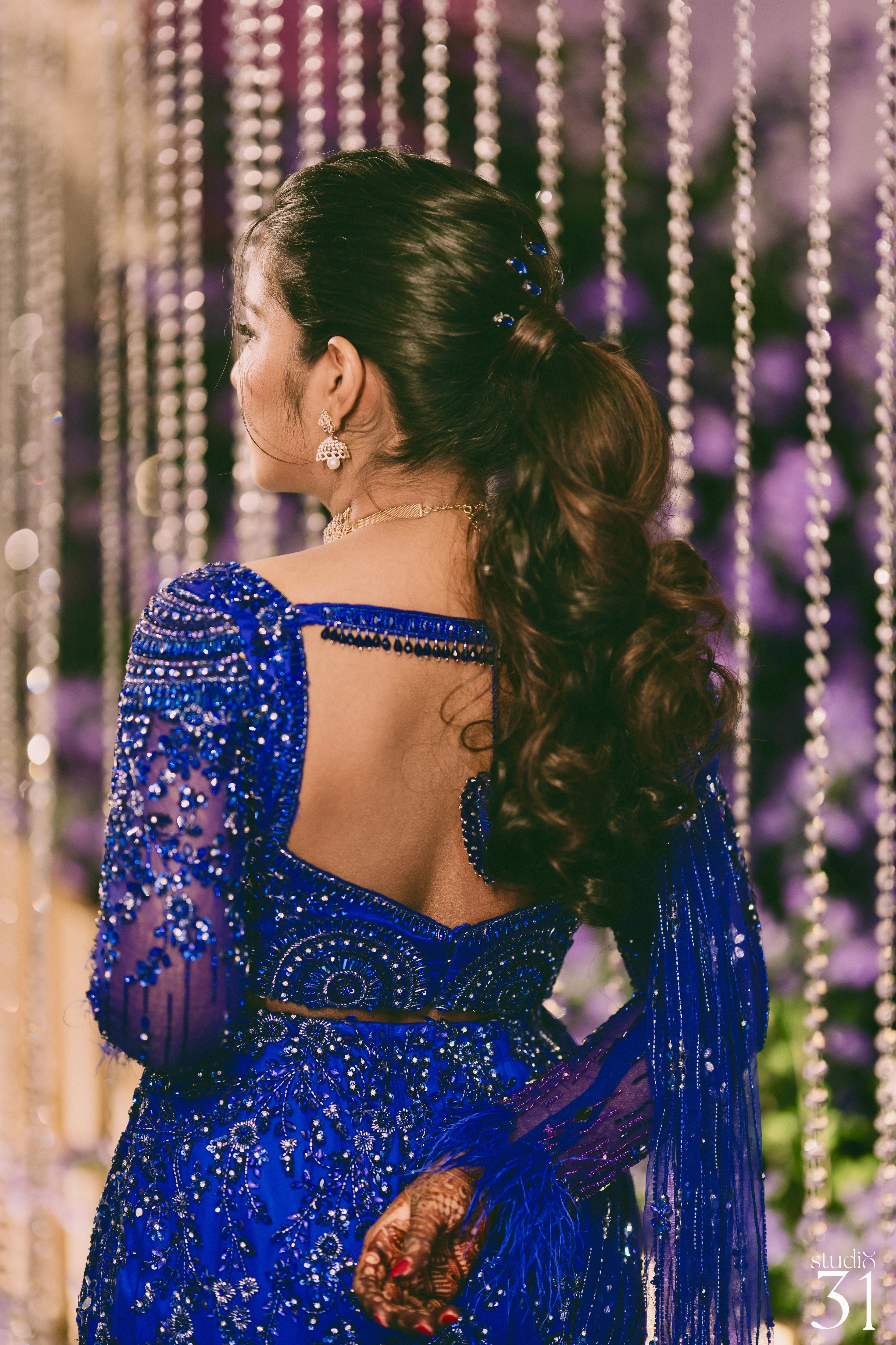 Bride Pooja posing for photo in a blue and purple mermaid draped lehenga by team Archana Karthick.