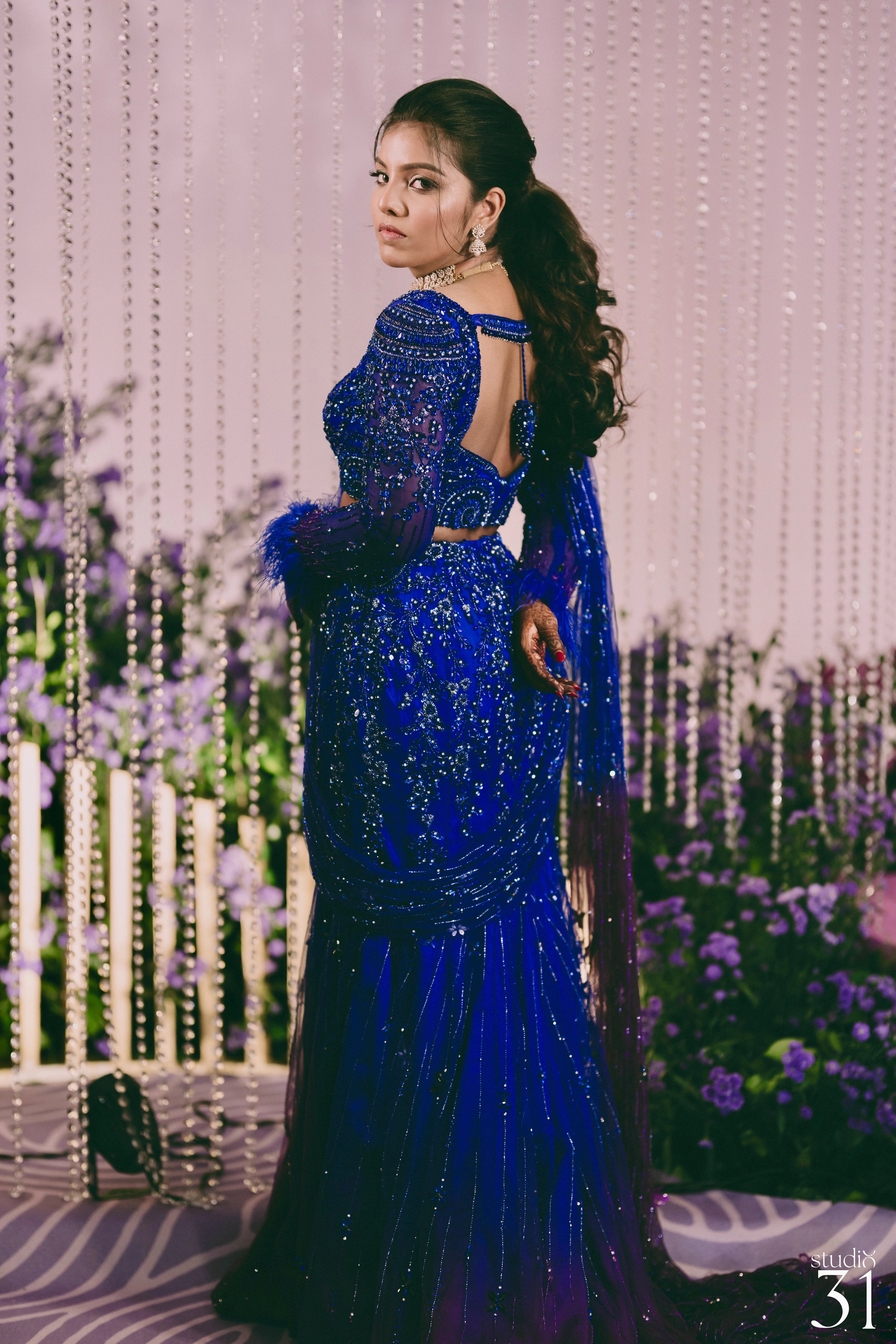Bride Pooja posing for photoshoot in a blue and purple mermaid draped lehenga by team Archana Karthick.