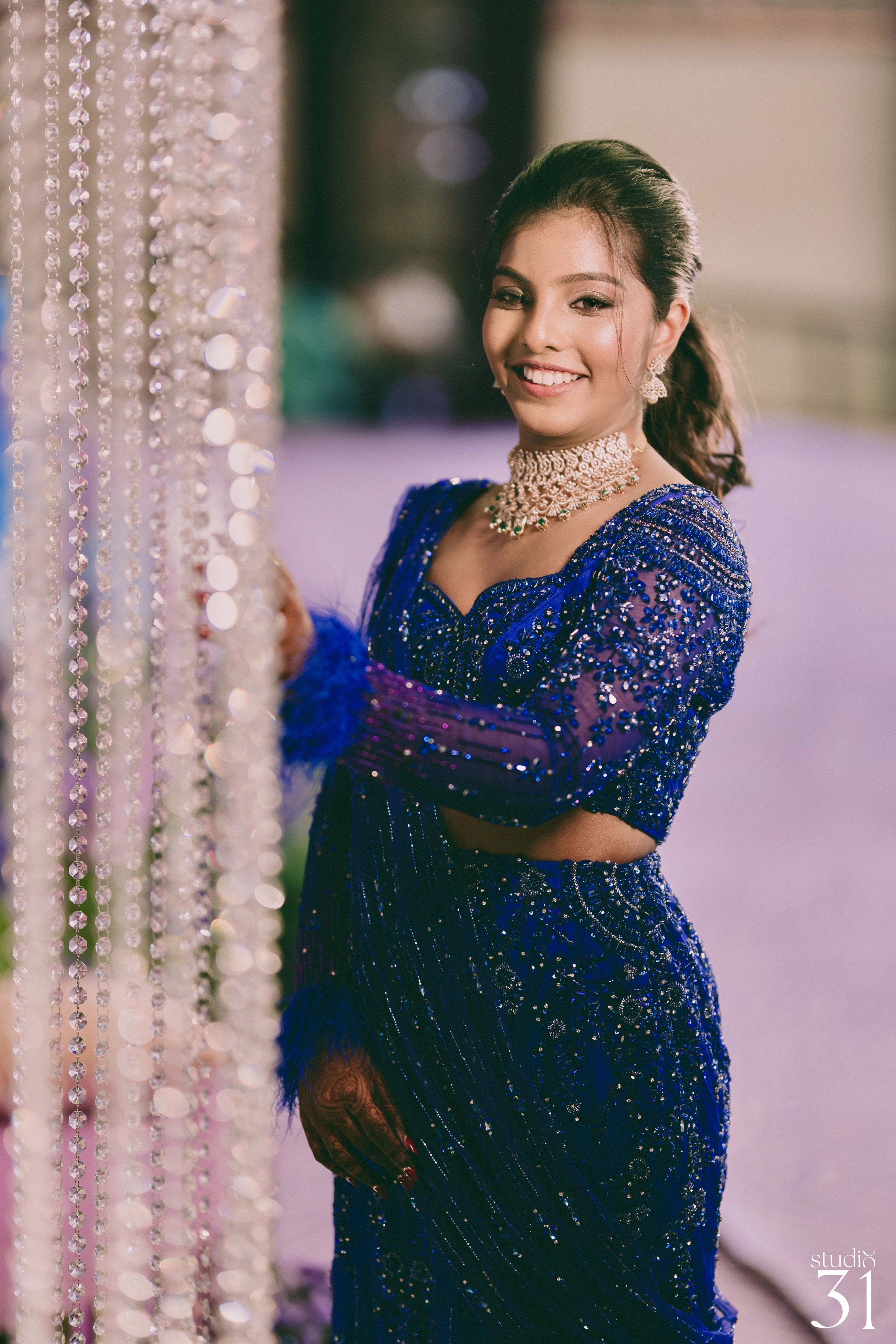 Bride Pooja smiling for photo in a blue and purple mermaid draped lehenga by team Archana Karthick.