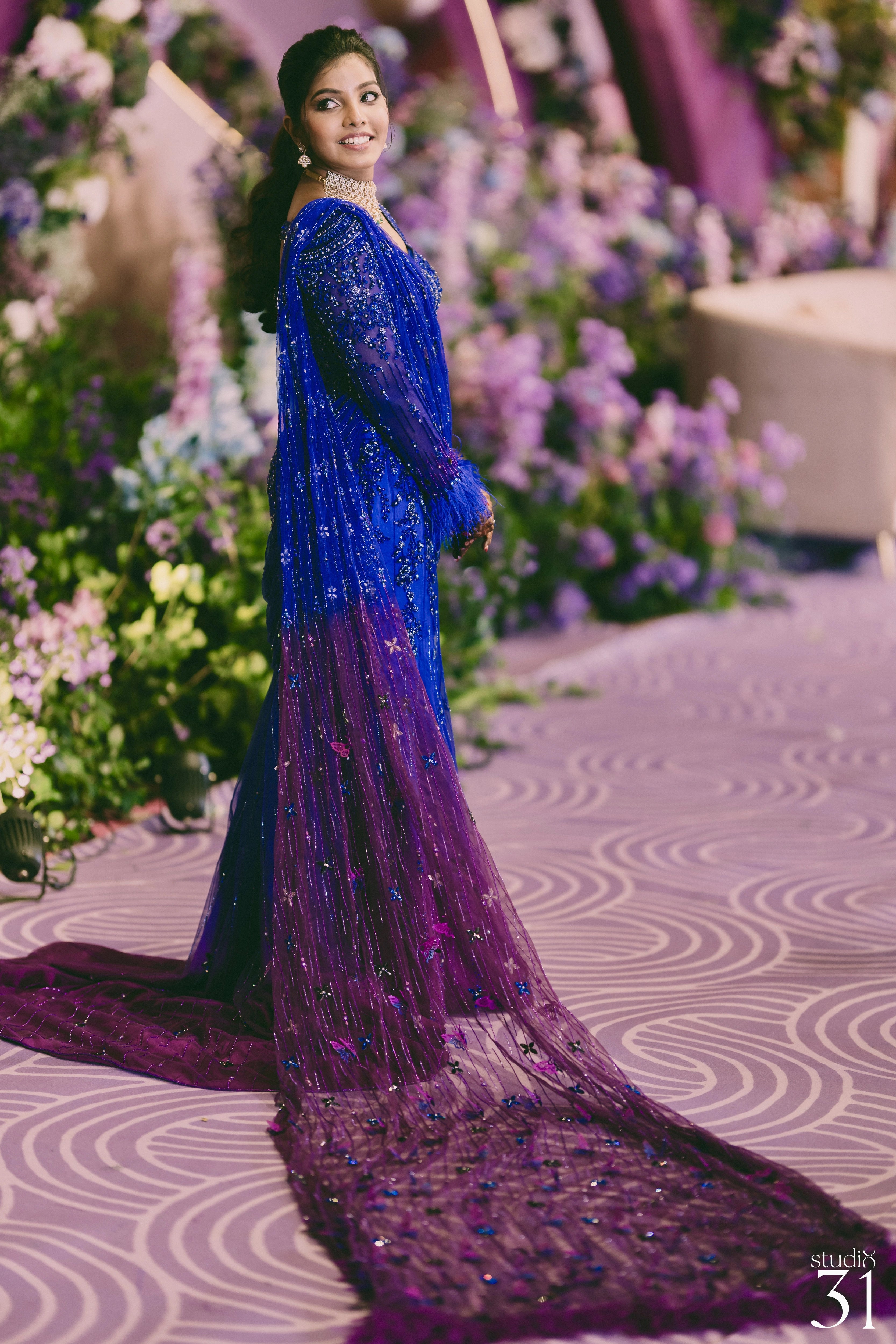 Bride Pooja smiling in a blue and purple mermaid draped lehenga by team Archana Karthick.