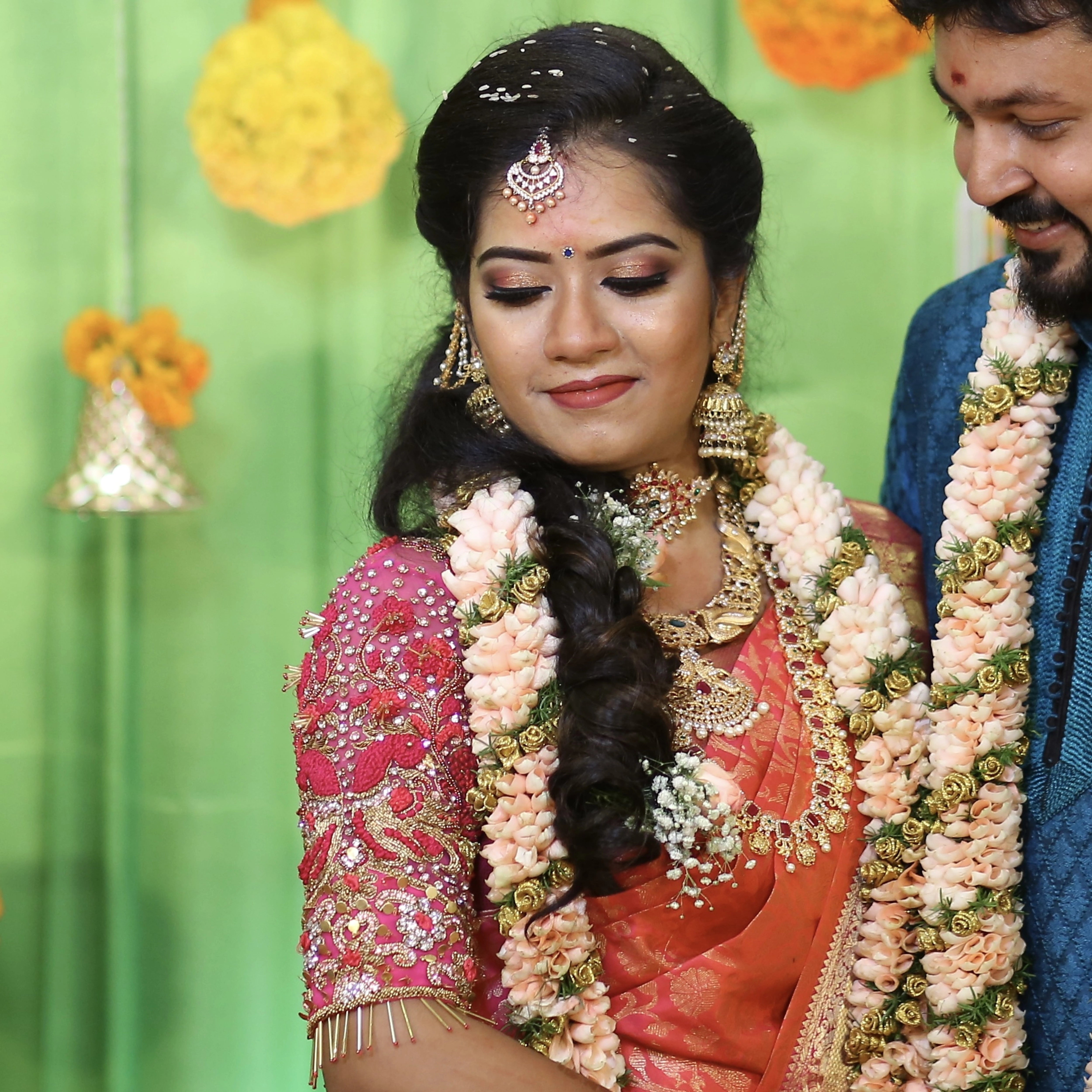 Bride Preethi Shiva smiling in a pink silk blouse handcrafted by team Archana Karthick.