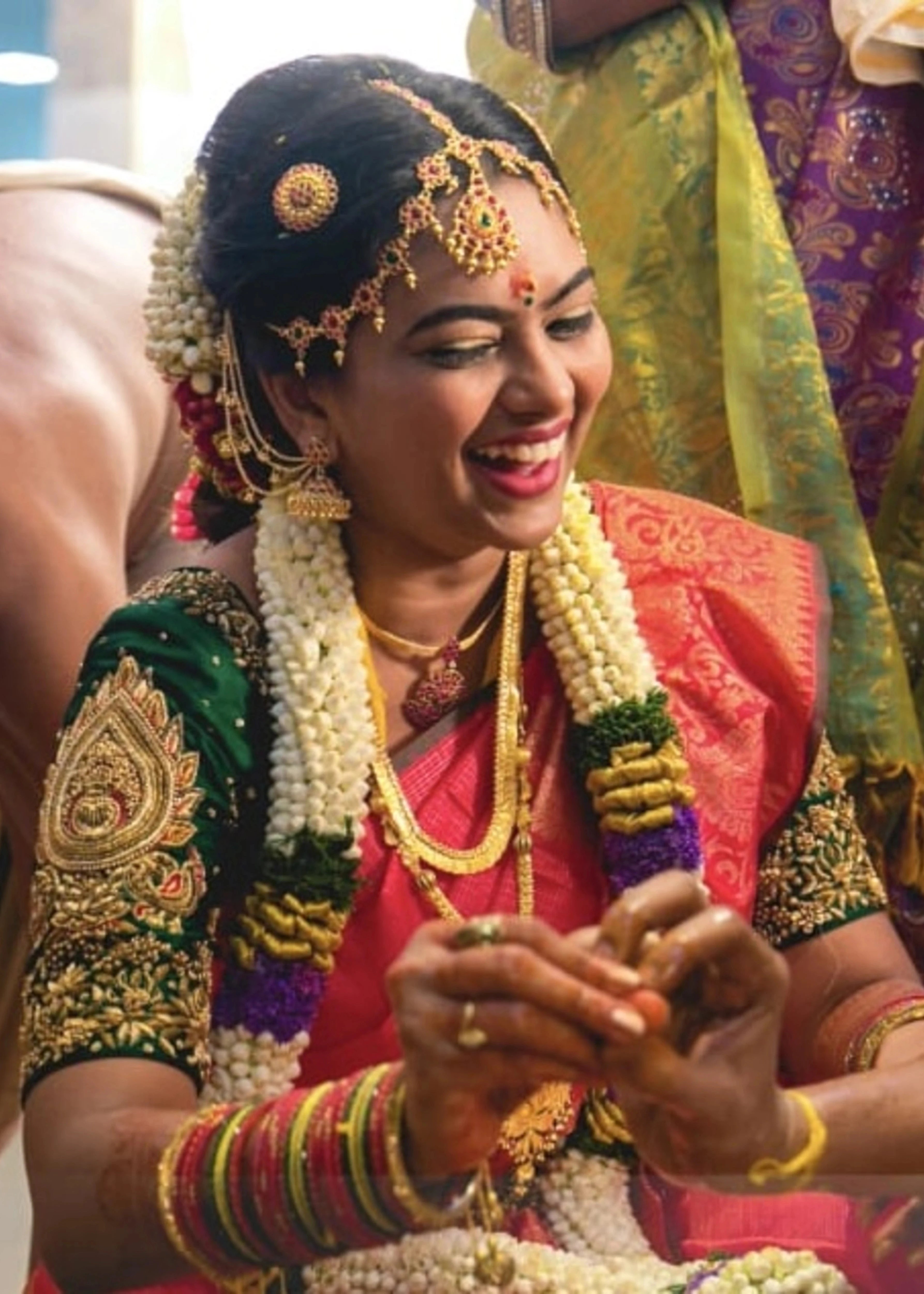Bride Priya Sathiyan laughing in a green silk blouse, intricately handcrafted with zardozi, resham, and beads by team Archana Karthick.