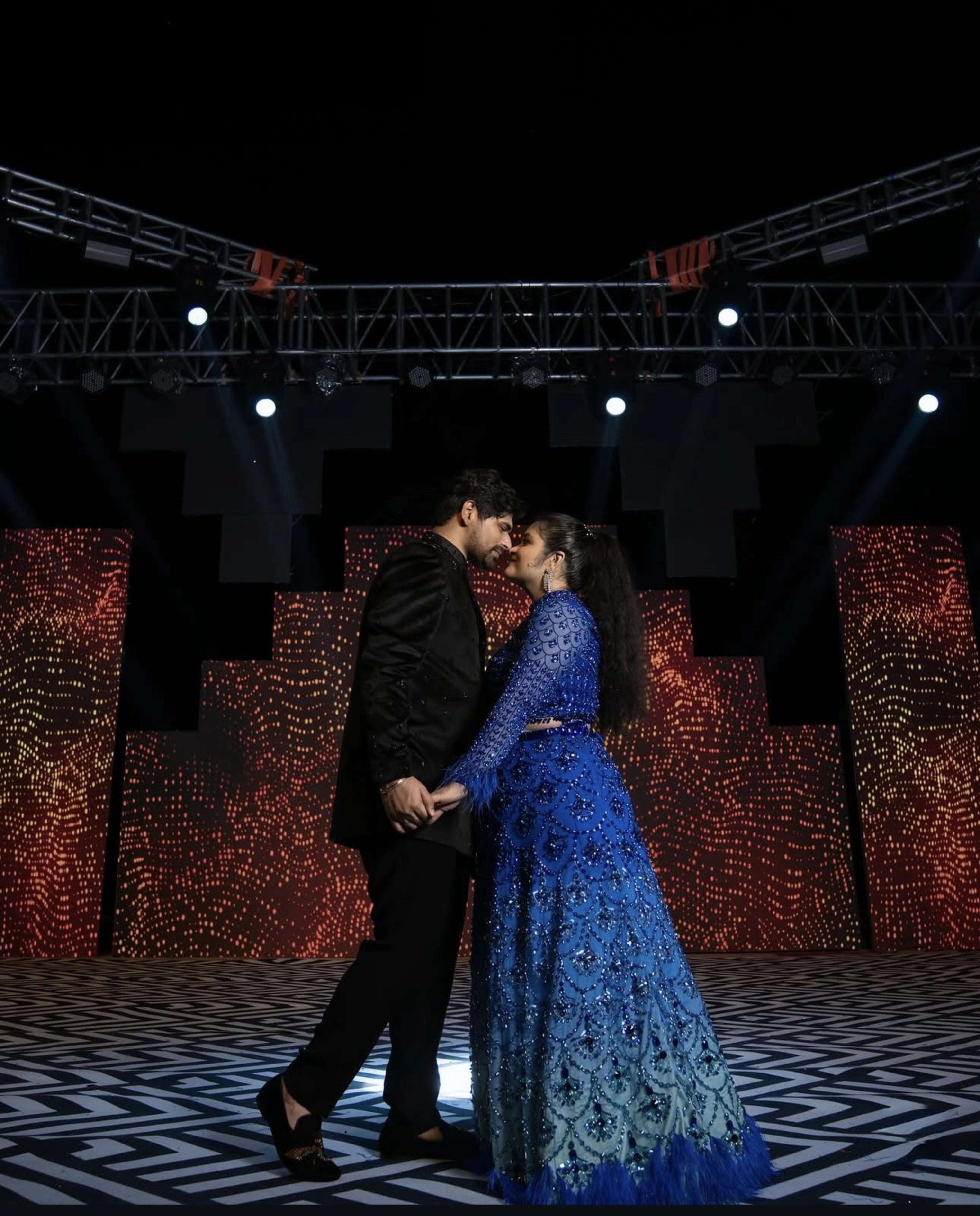 Bride Rasagnya posing with groom in a peacock themed blue tulle lehenga, handcrafted with rhinestones, crystals, cutdana, sequins and feathers by team Archana Karthick.