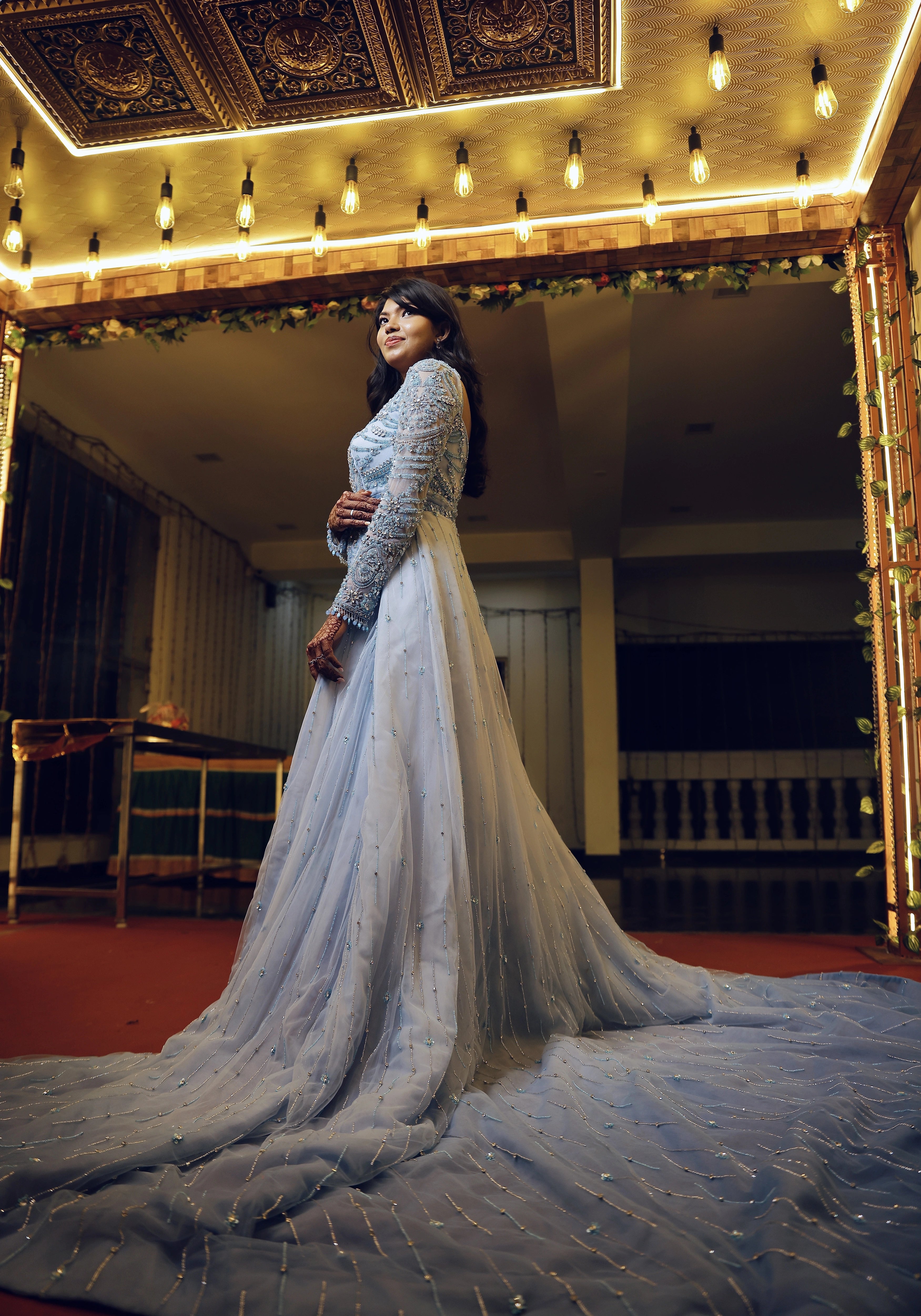 Bride Raxana smiling for photoshoot in a blue tulle mermaid gown by team Archana Karthick.