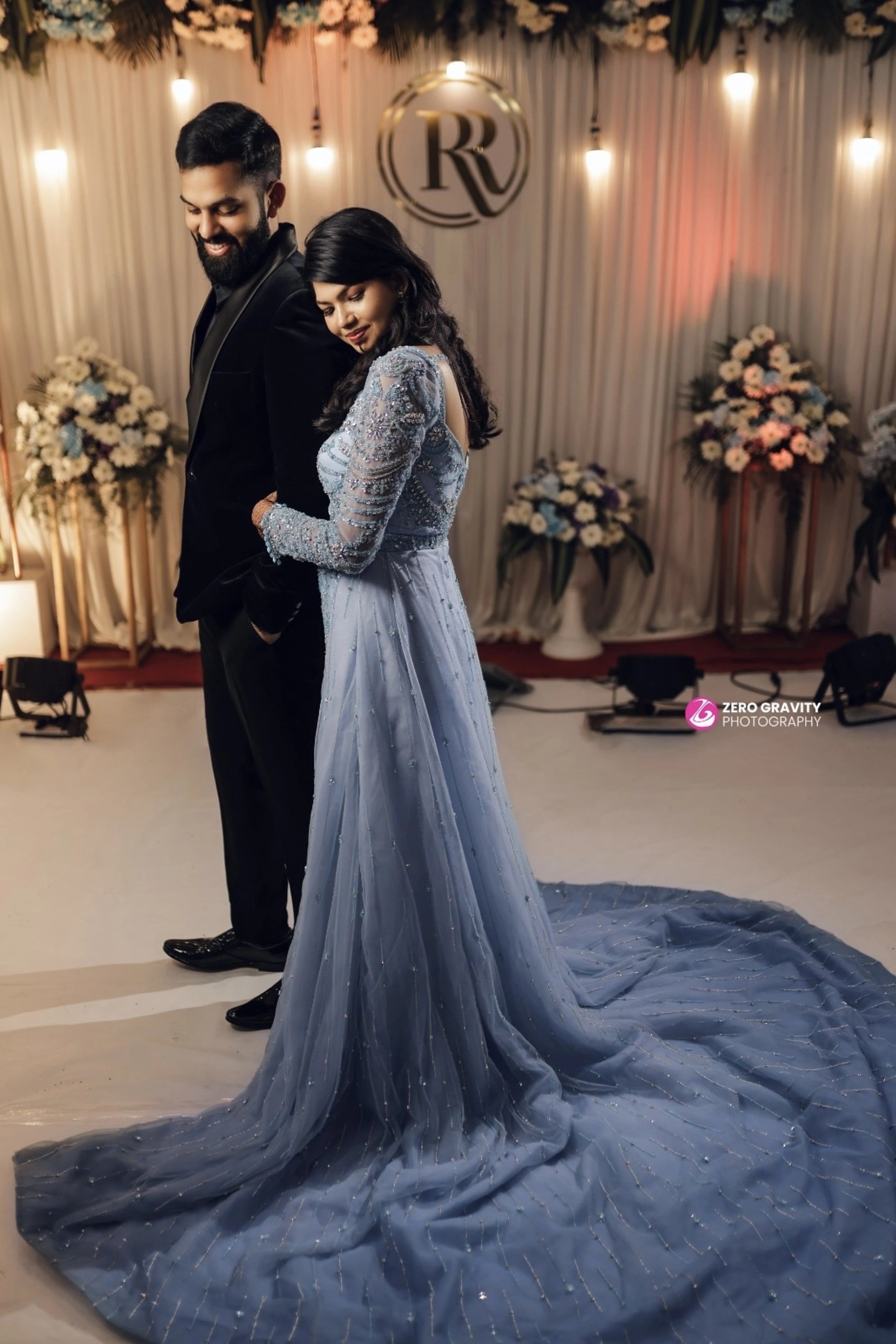 Bride Raxana with groom smiling for photograph in a blue tulle mermaid gown by team Archana Karthick.