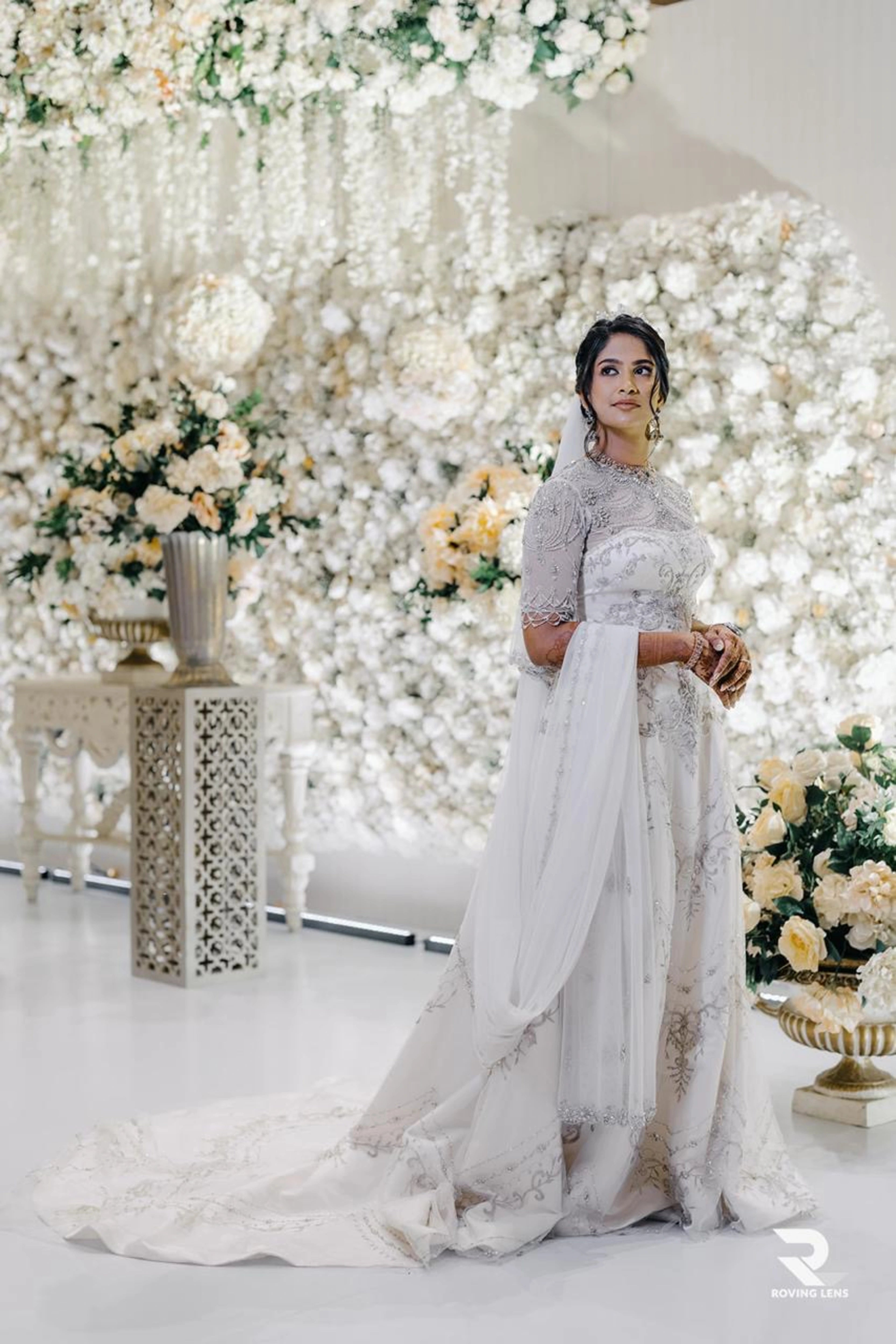 Bride Roushni posing on stage in a white gown for her church wedding by team Archana Karthick.