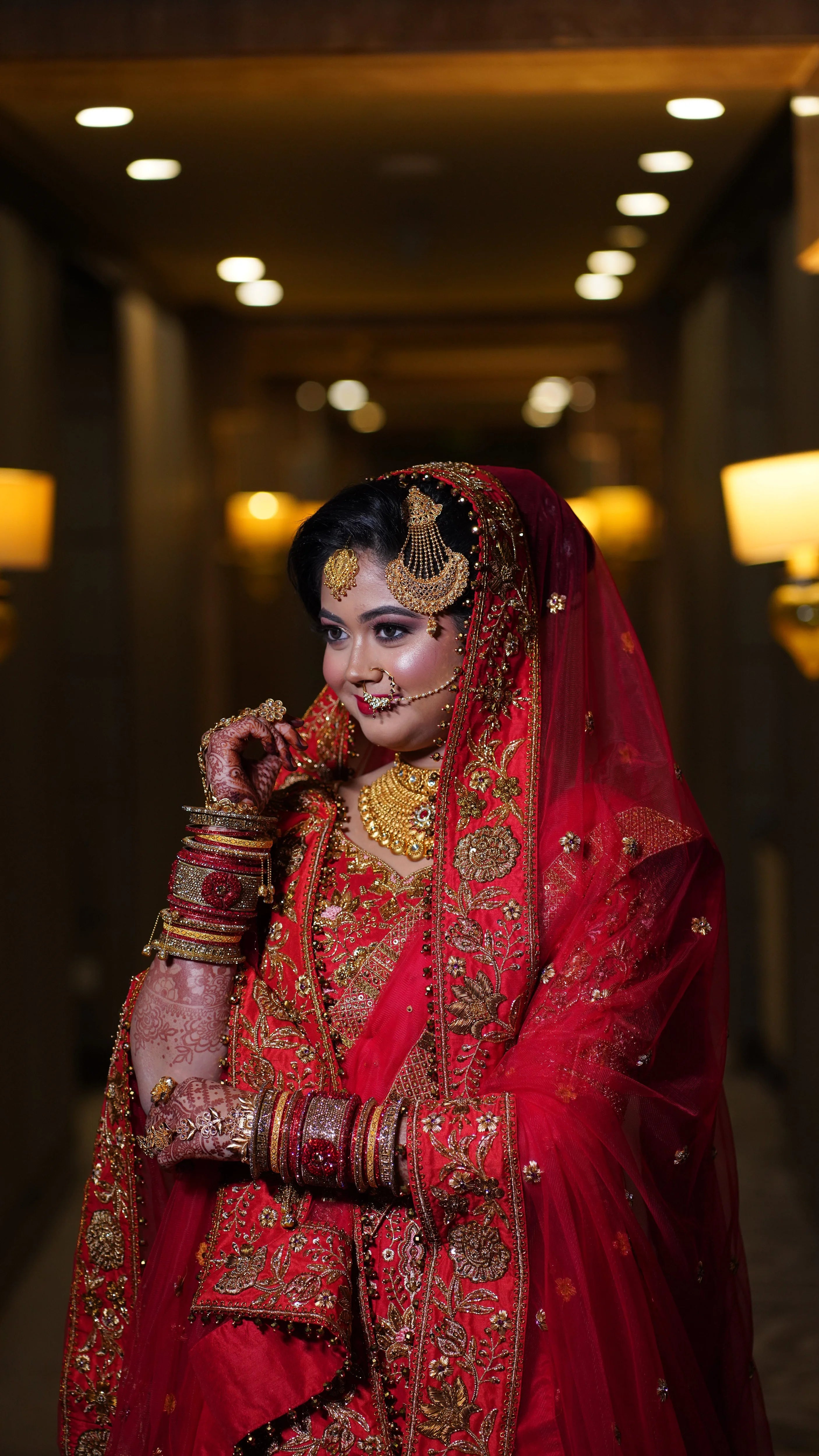 Bride Saba smiling in a red raw silk lehenga with a veil and dupatta handcrafted by team Archana Karthick.
