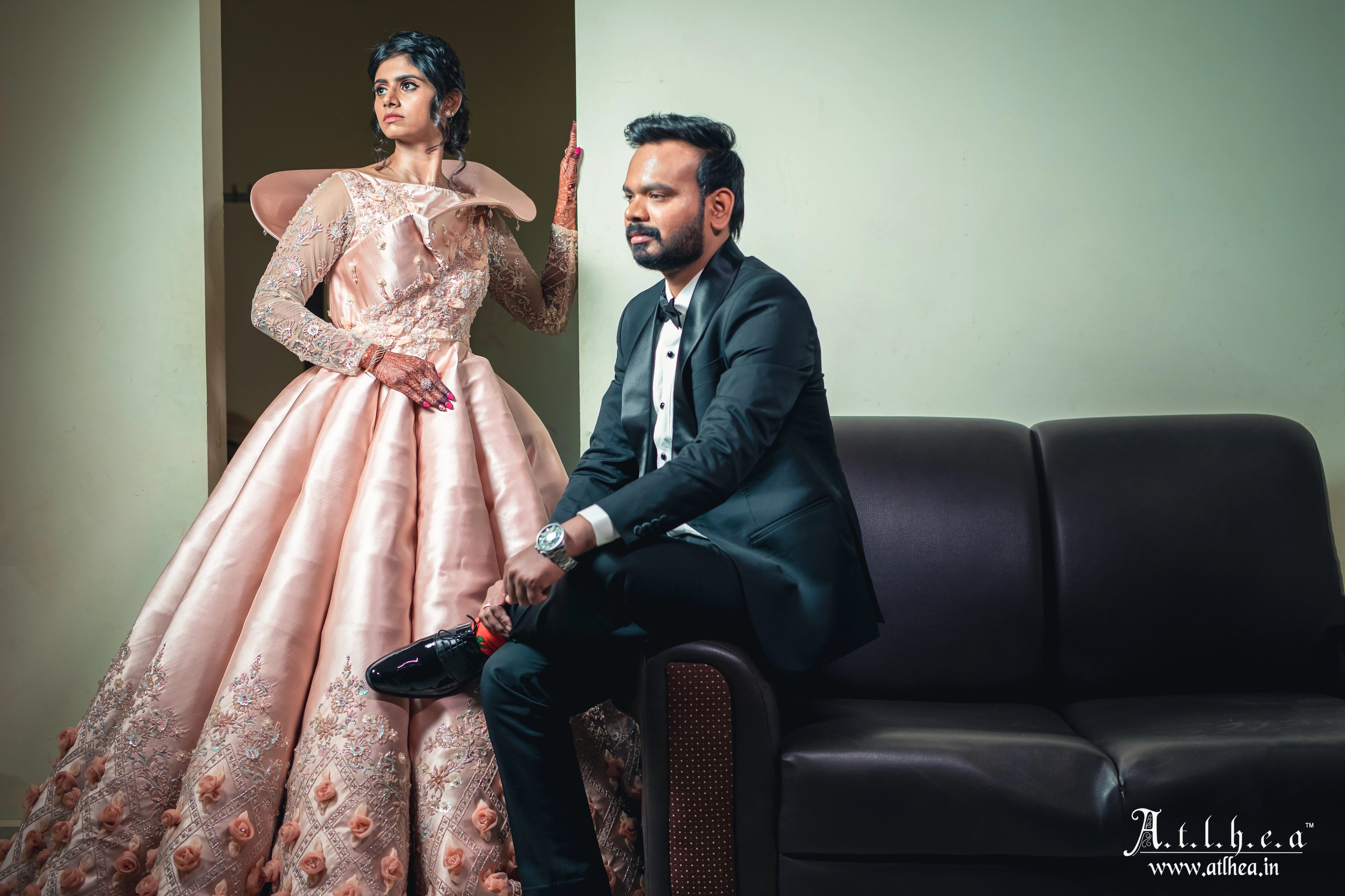 Bride Sahana smiling with groom in a peach cream satin structured ball gown, handcrafted intricately with applique, sequins, stones and cutdana by team Archana Karthick.