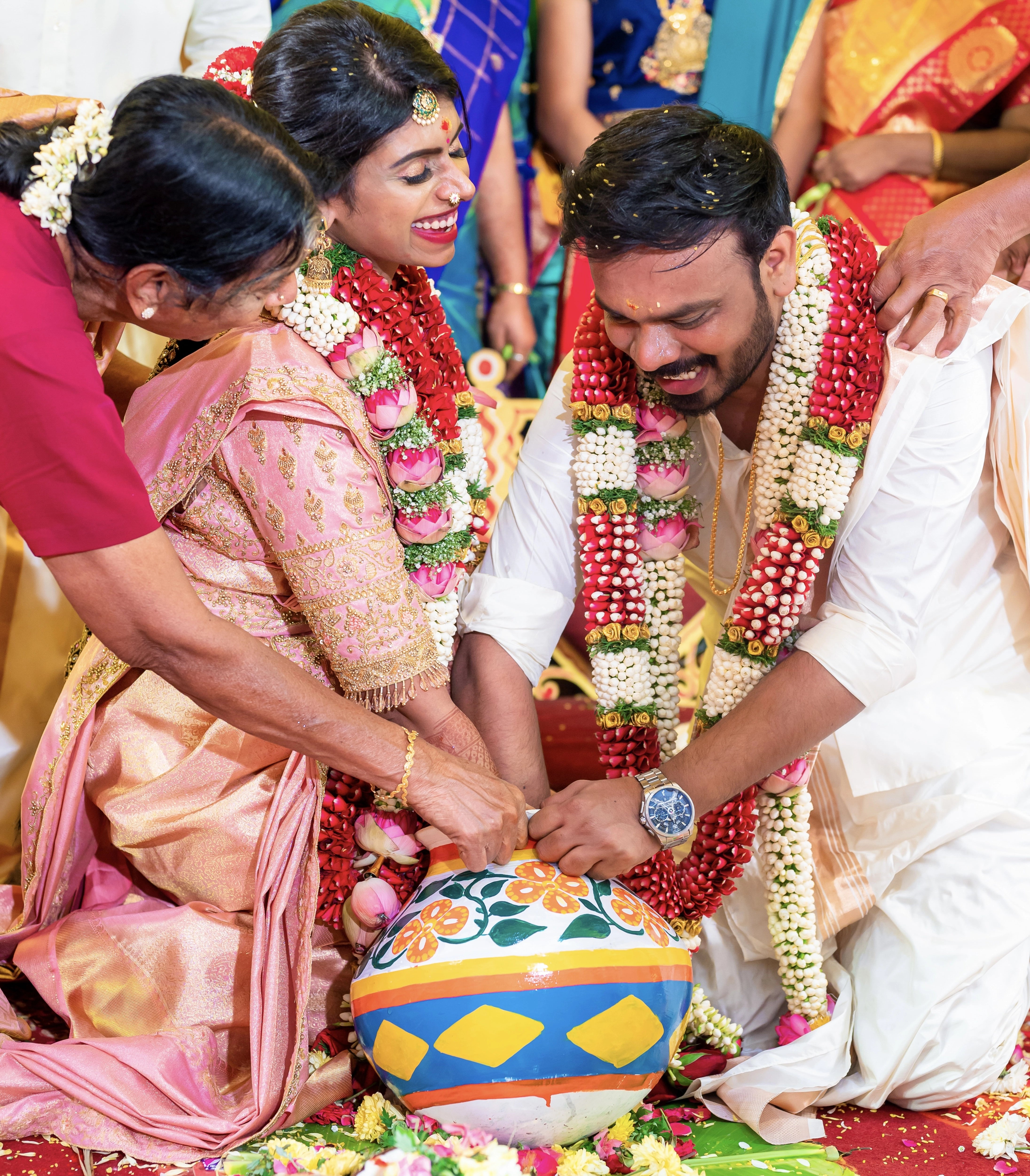 Bride Sahana smiling with groom in a peach cream silk blouse and belt, handcrafted intricately with beads, cutdana, zari, crystals and resham by team Archana Karthick.