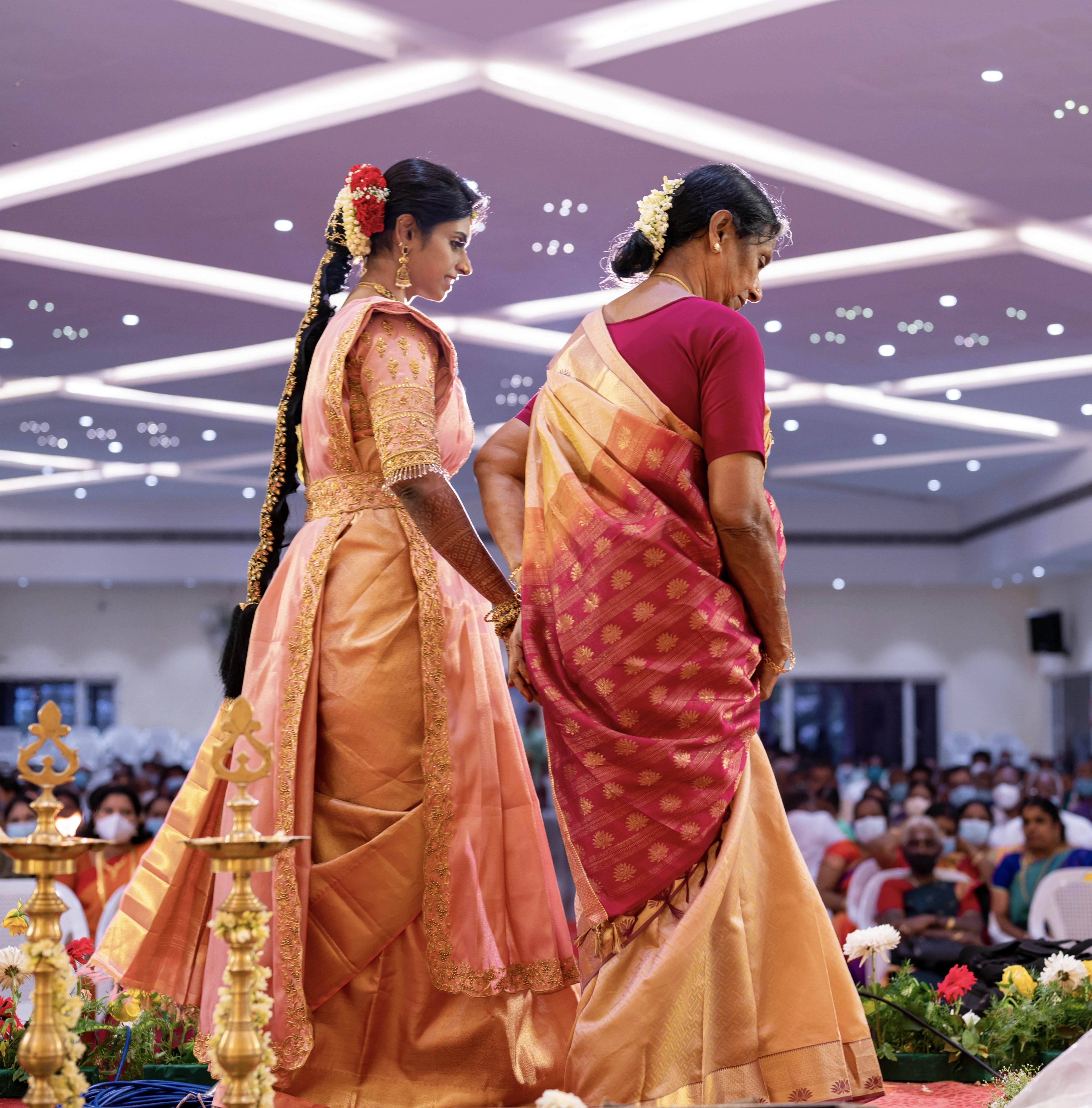 Bride Sahana walking in a peach cream silk blouse and belt, handcrafted intricately with beads, cutdana, zari, crystals and resham by team Archana Karthick.