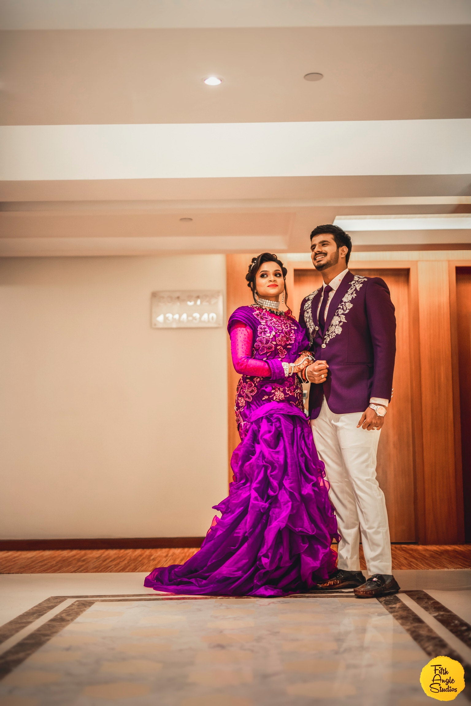 Bride Sai Sridevi & Groom posing for photo in a purple gown and suit handcrafted by team Archana Karthick.